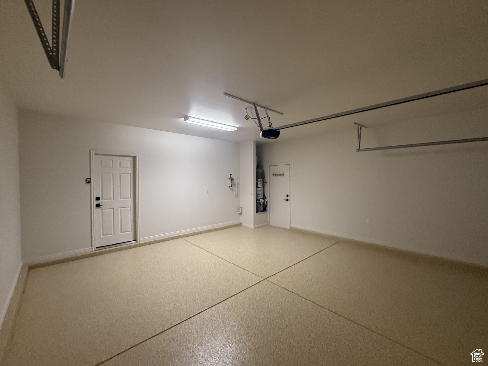 Garage with baseboards, secured water heater, and a garage door opener