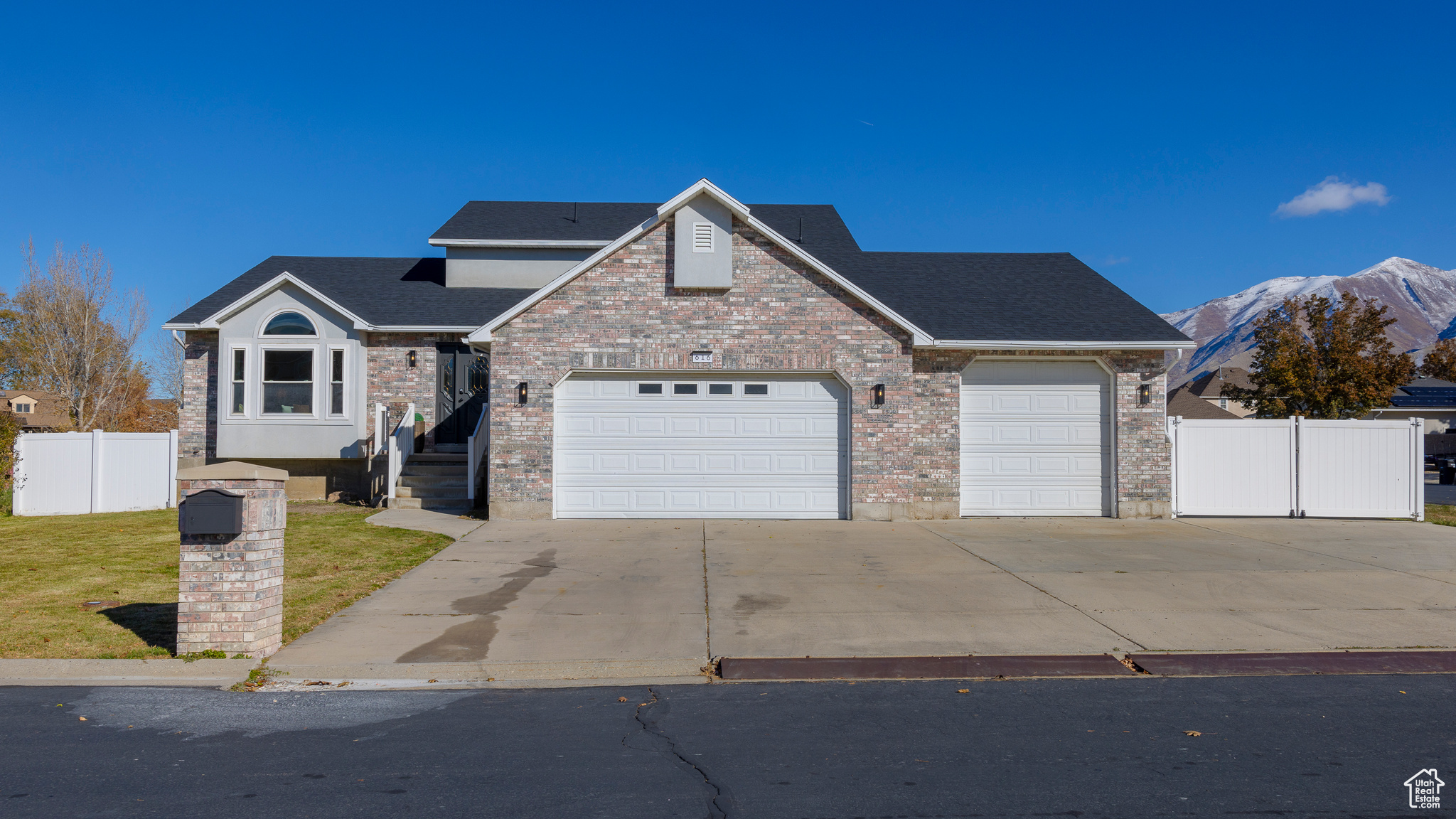 Traditional home featuring an attached garage, brick siding, fence, driveway, and a front lawn
