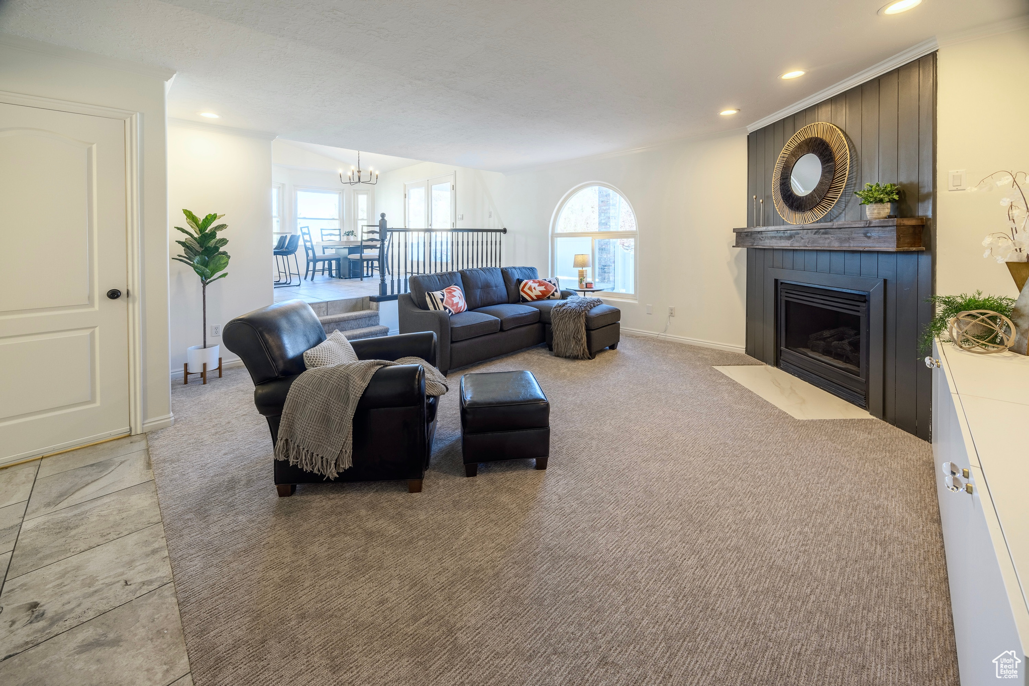 Living area featuring light carpet, baseboards, a fireplace, a chandelier, and recessed lighting