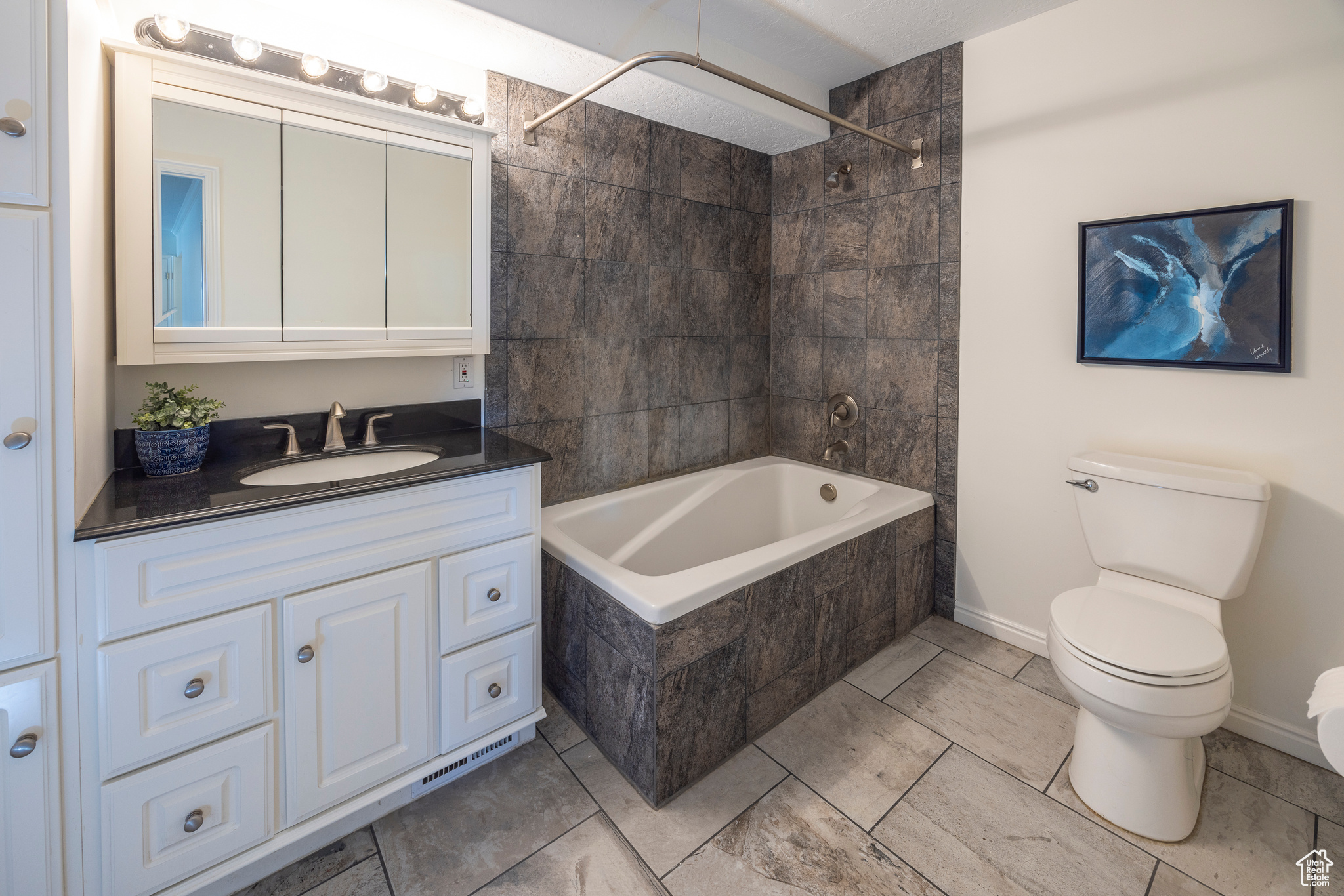 Bathroom with baseboards, bathing tub / shower combination, toilet, and vanity