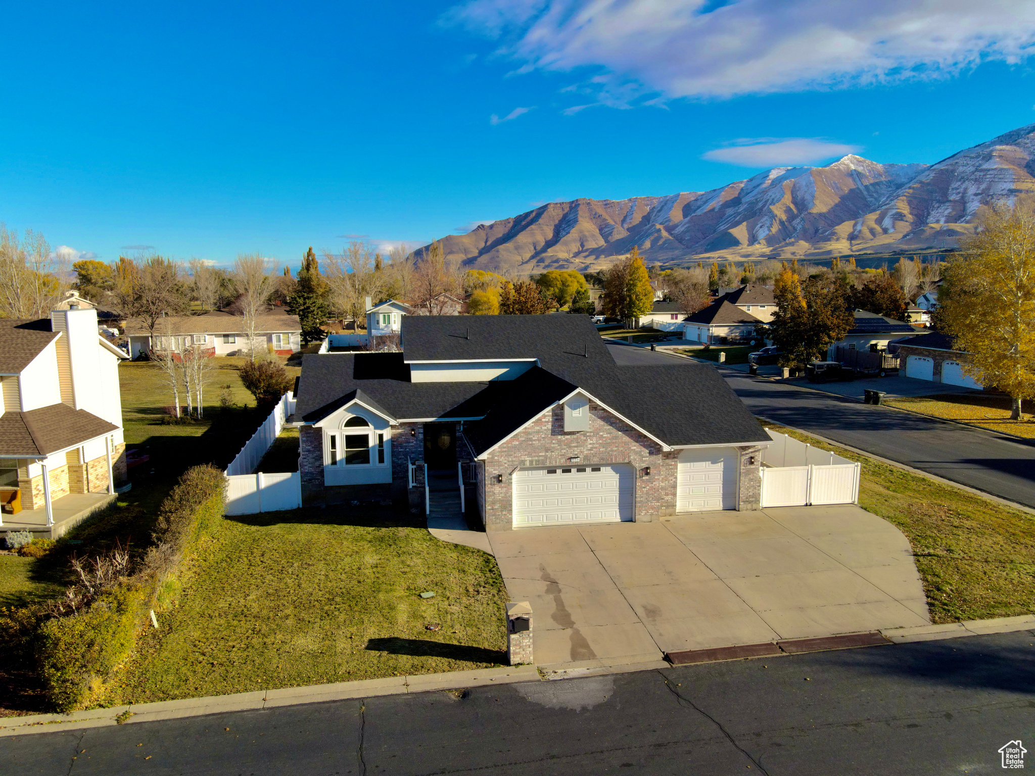 View of front of house with concrete driveway, fence, a mountain view, a garage, and a front lawn