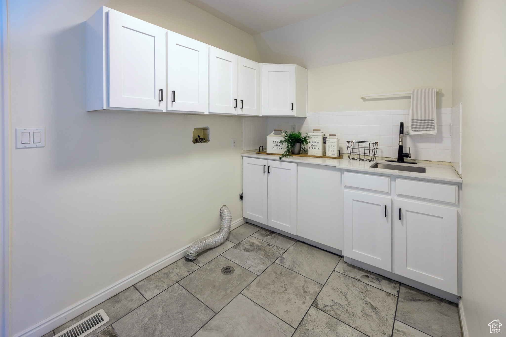 Laundry room featuring washer hookup, a sink, cabinet space, and baseboards