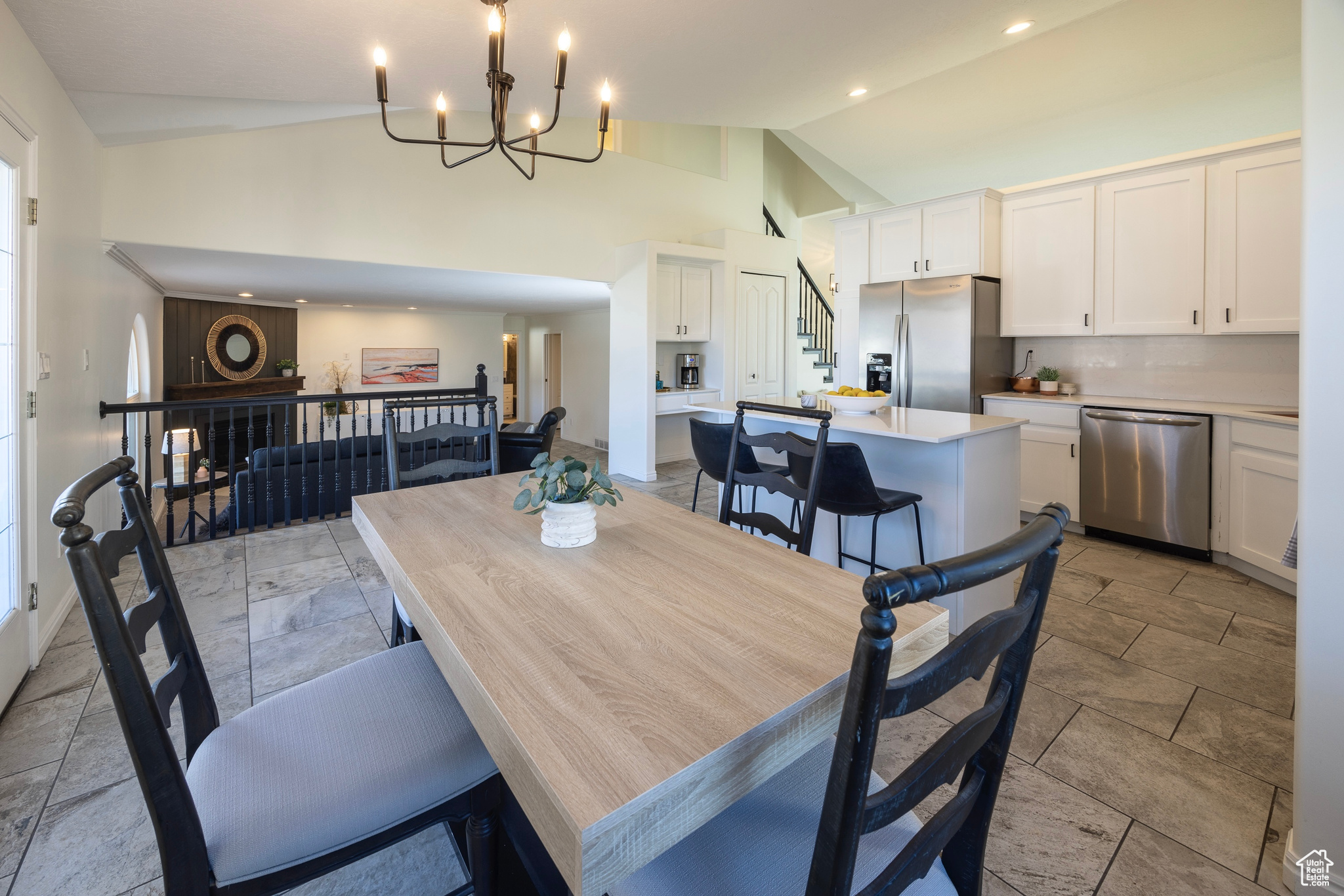 Dining area with high vaulted ceiling, recessed lighting, baseboards, stairs, and an inviting chandelier