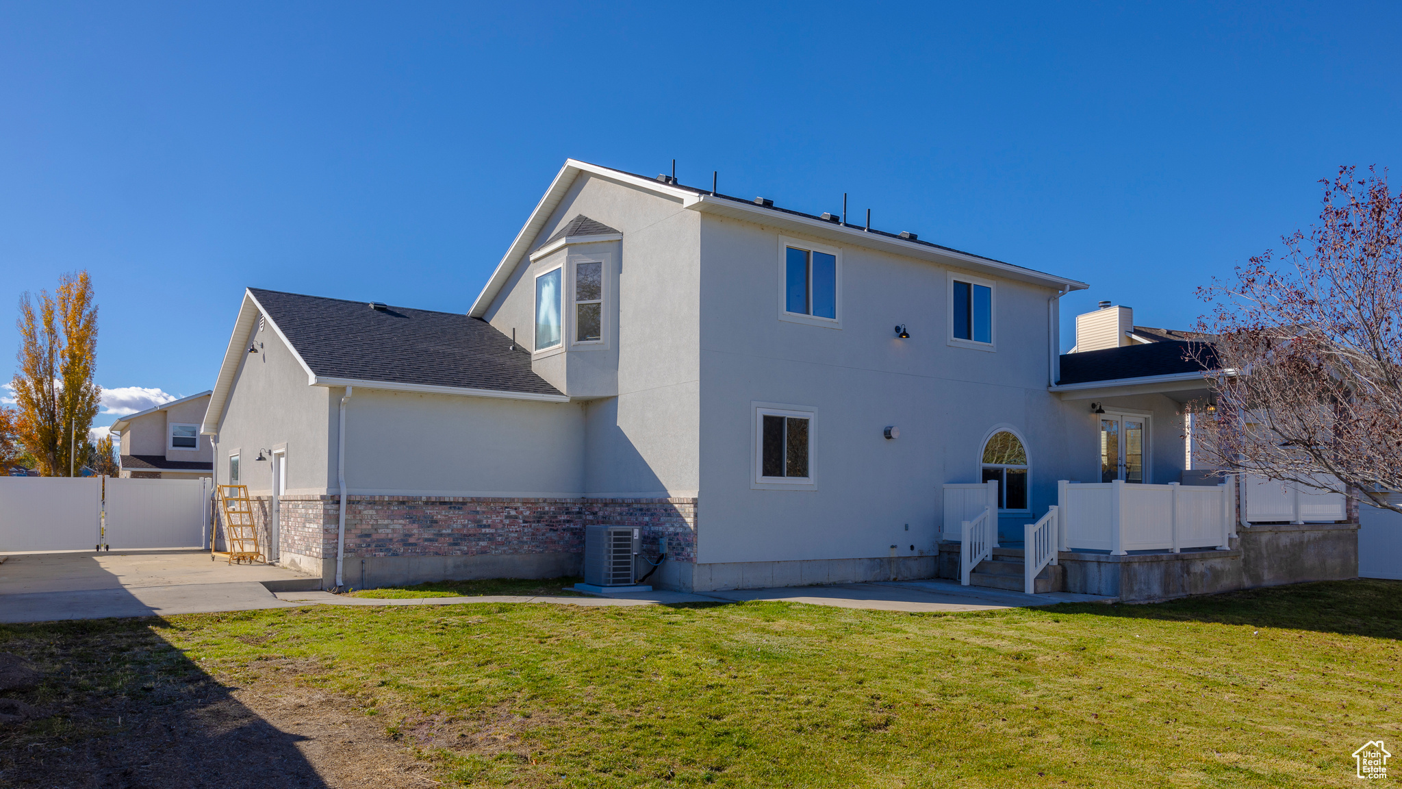 Rear view of house featuring a patio area, fence, central AC unit, and a yard