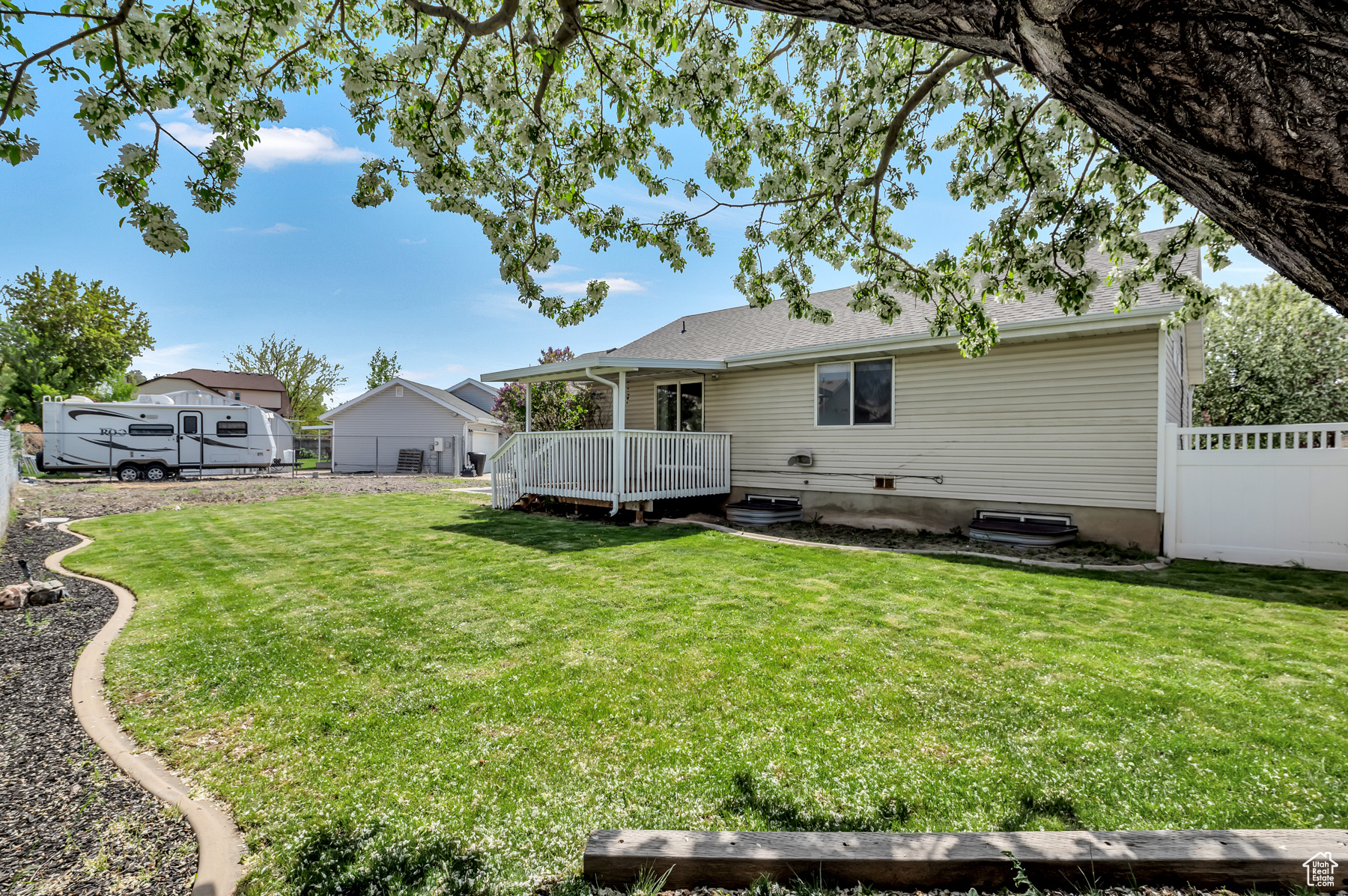 Rear view of house featuring a lawn, a deck, and fence