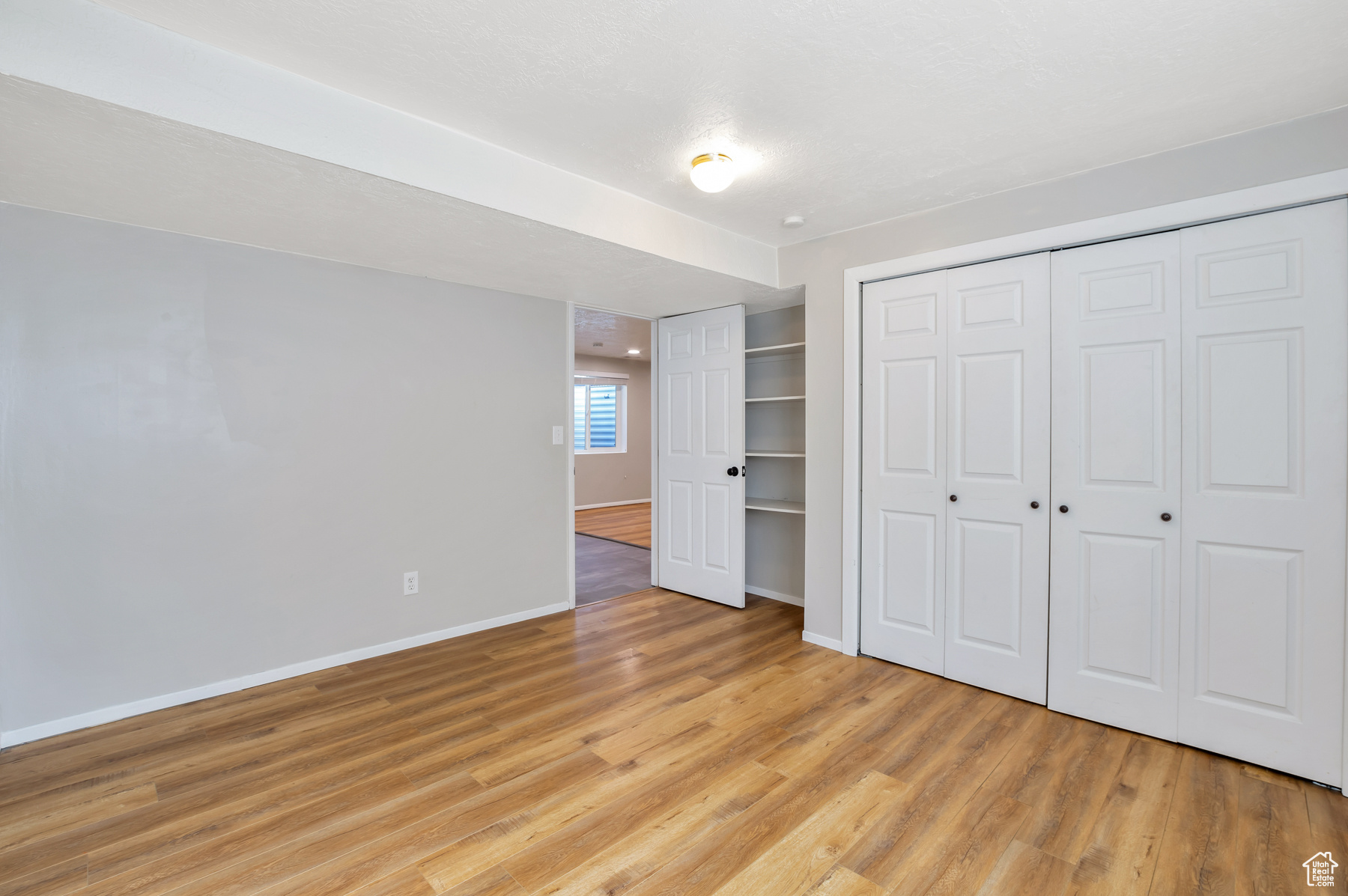 Unfurnished bedroom featuring a closet, light wood-type flooring, and baseboards