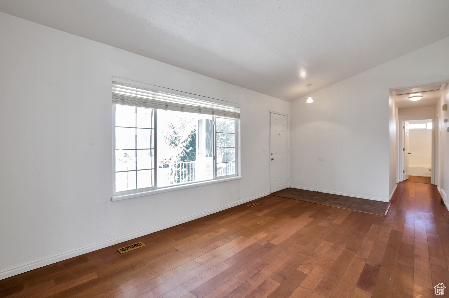 Unfurnished room with visible vents, lofted ceiling, baseboards, and dark wood-style flooring