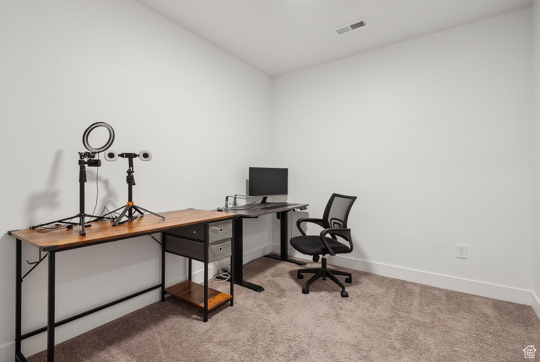 Carpeted home office with visible vents and baseboards