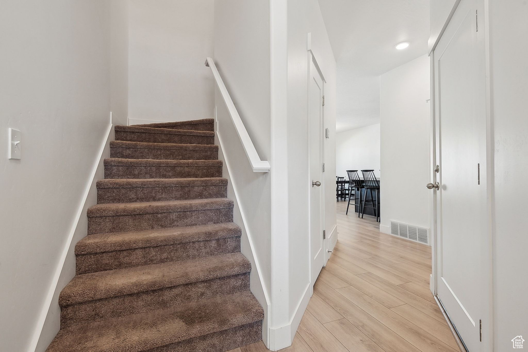 Staircase featuring wood finished floors, visible vents, and baseboards