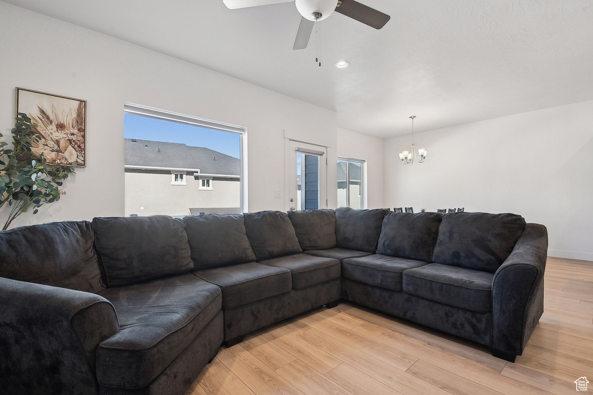 Living area featuring ceiling fan with notable chandelier, light wood-type flooring, and recessed lighting