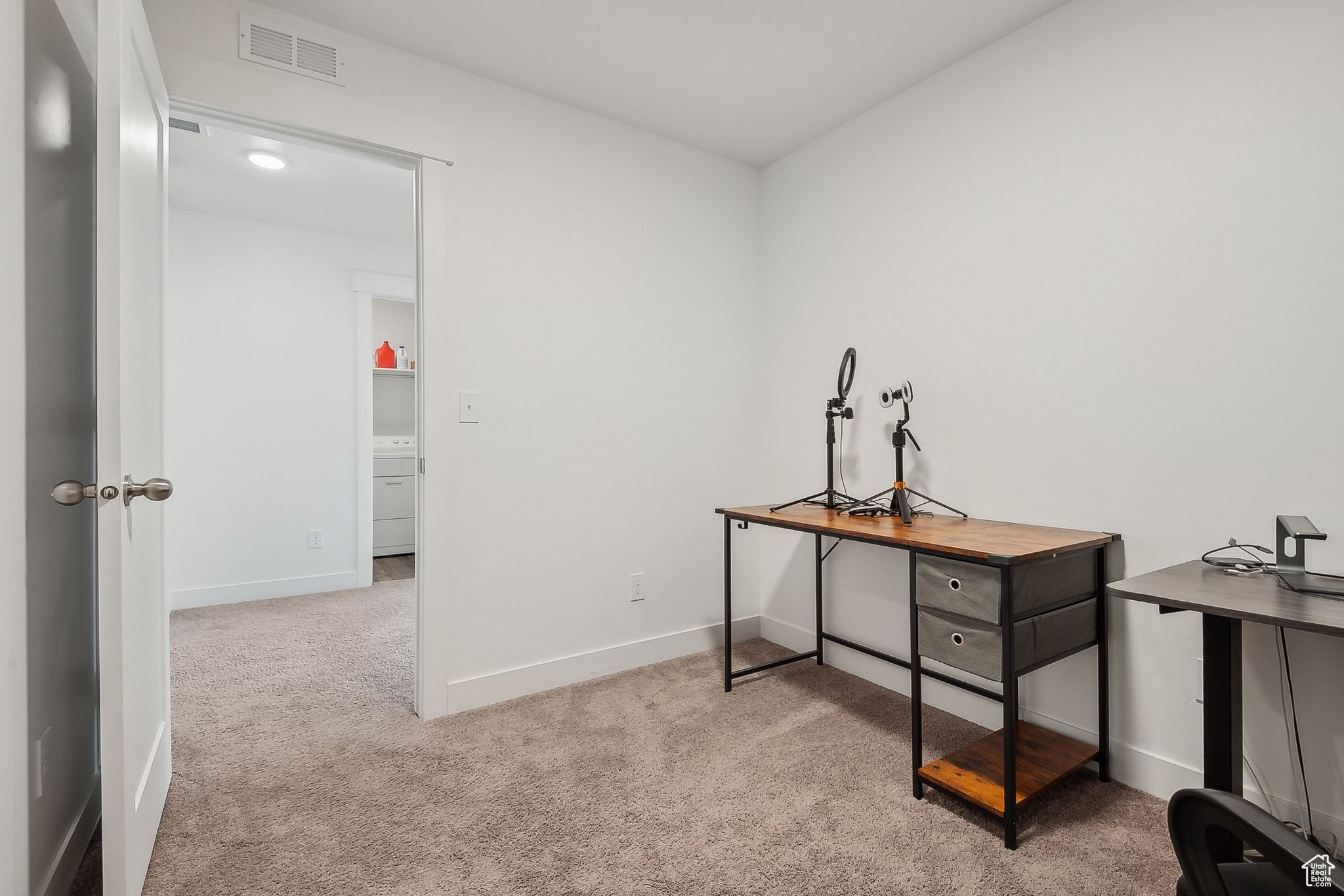 Office area featuring baseboards, visible vents, and carpet flooring