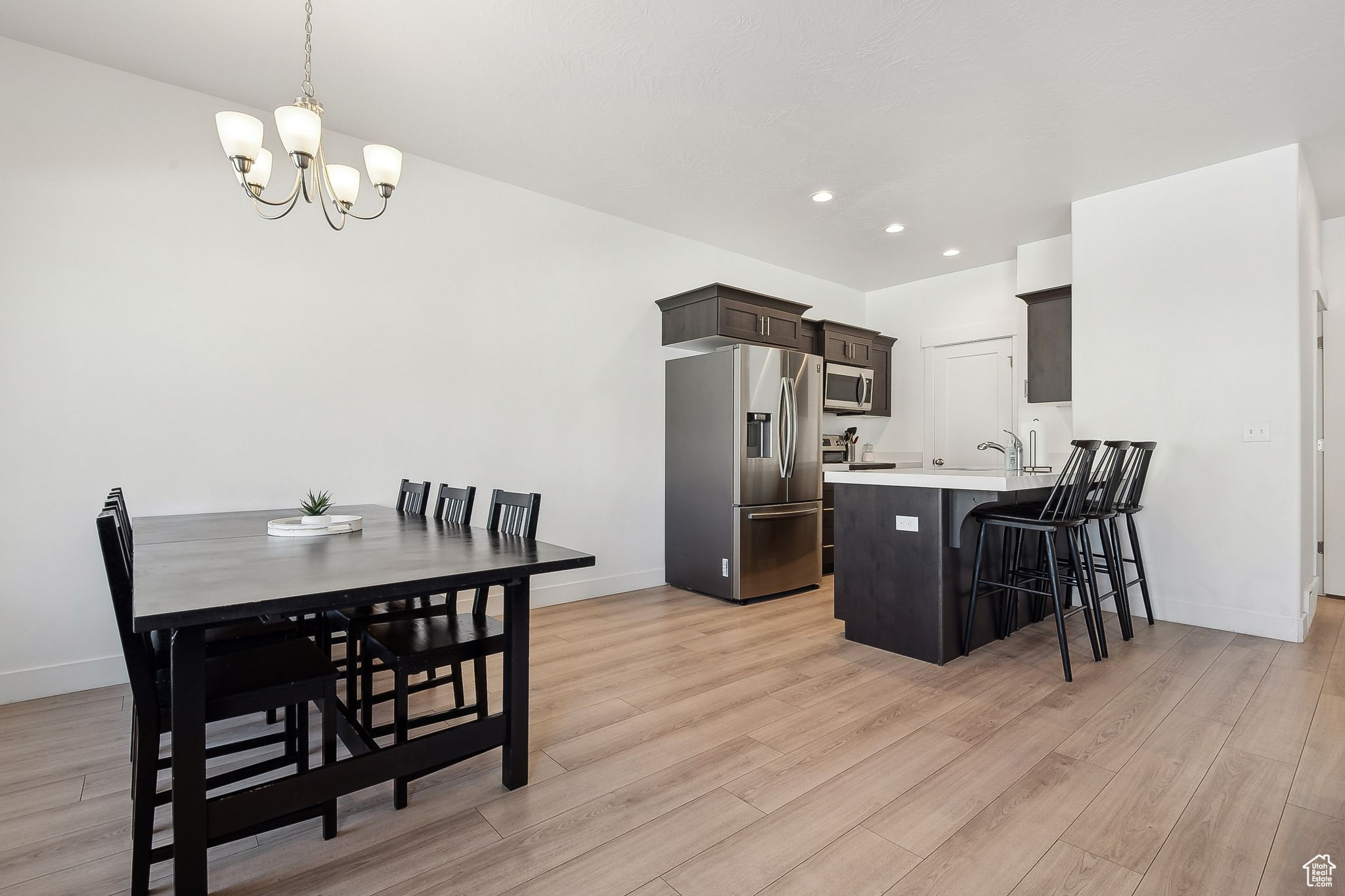 Dining space with baseboards, recessed lighting, light wood-style flooring, and an inviting chandelier