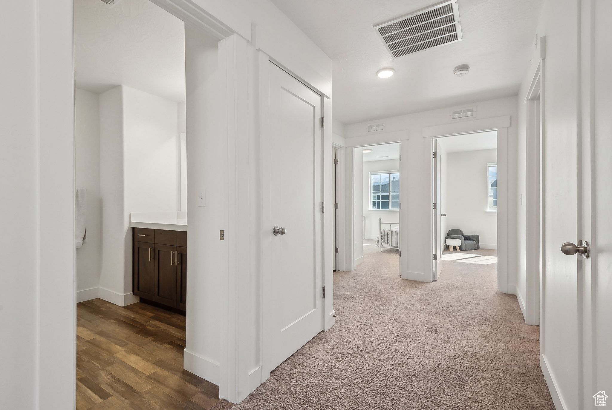 Corridor with carpet flooring, visible vents, and baseboards