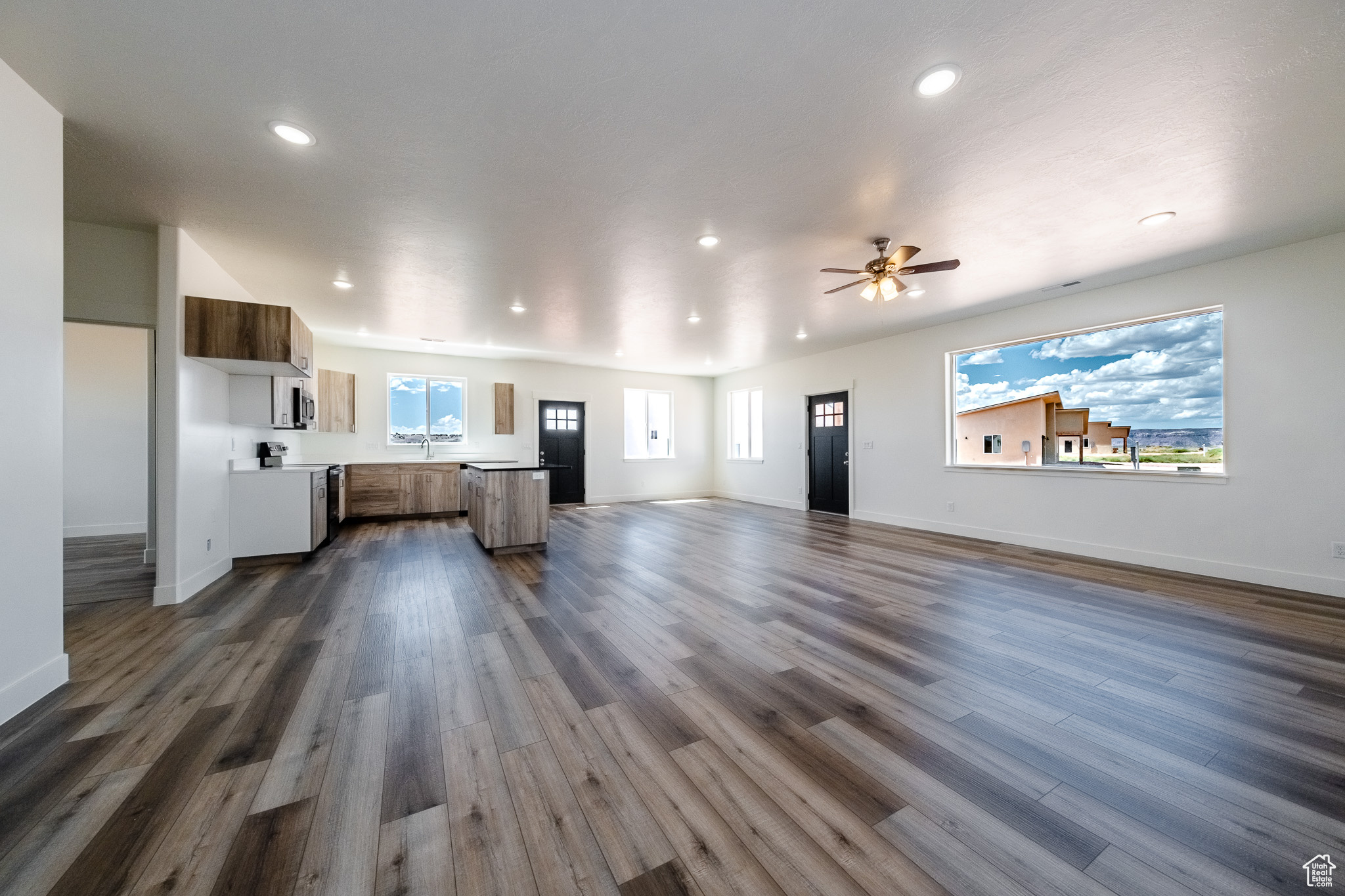 Unfurnished living room with dark wood finished floors, recessed lighting, baseboards, and a ceiling fan