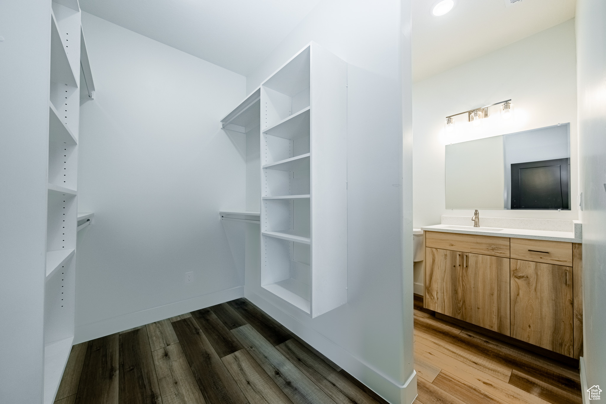 Walk in closet featuring dark wood-style flooring and a sink