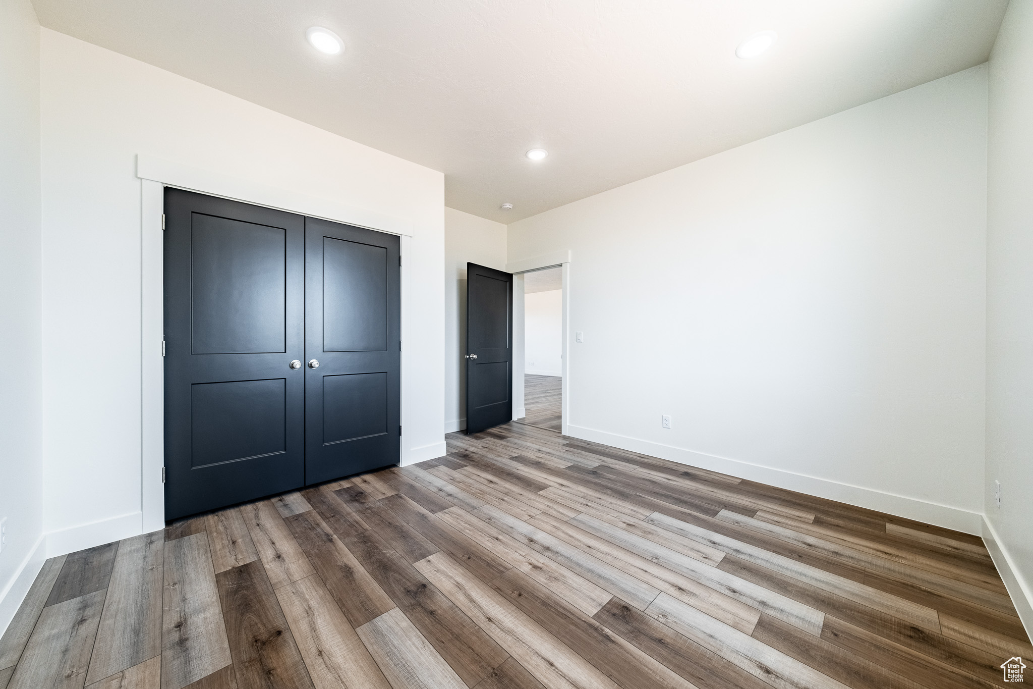 Unfurnished bedroom featuring a closet, recessed lighting, baseboards, and wood finished floors