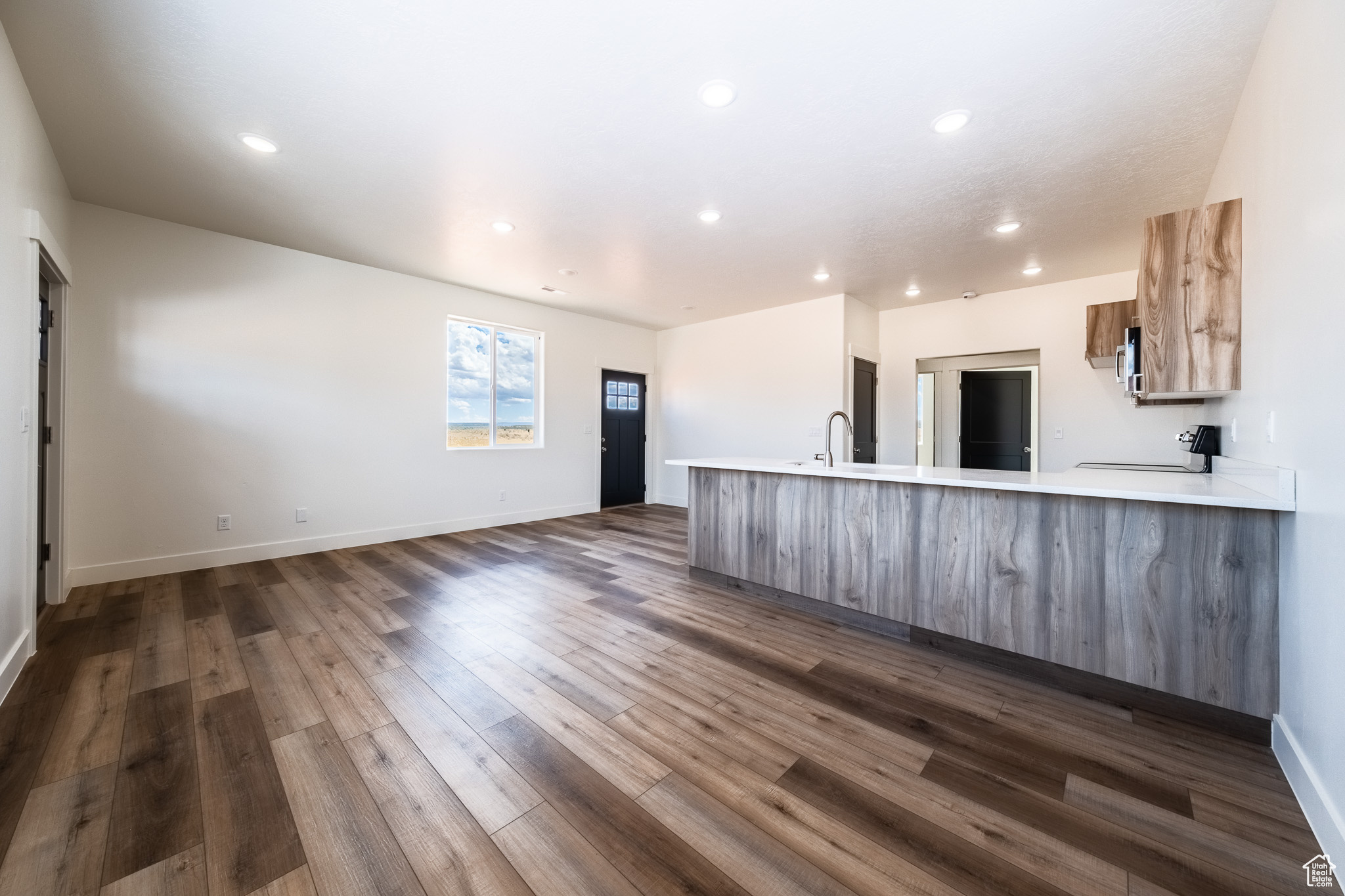 Kitchen featuring a peninsula, dark wood-style flooring, a sink, light countertops, and modern cabinets