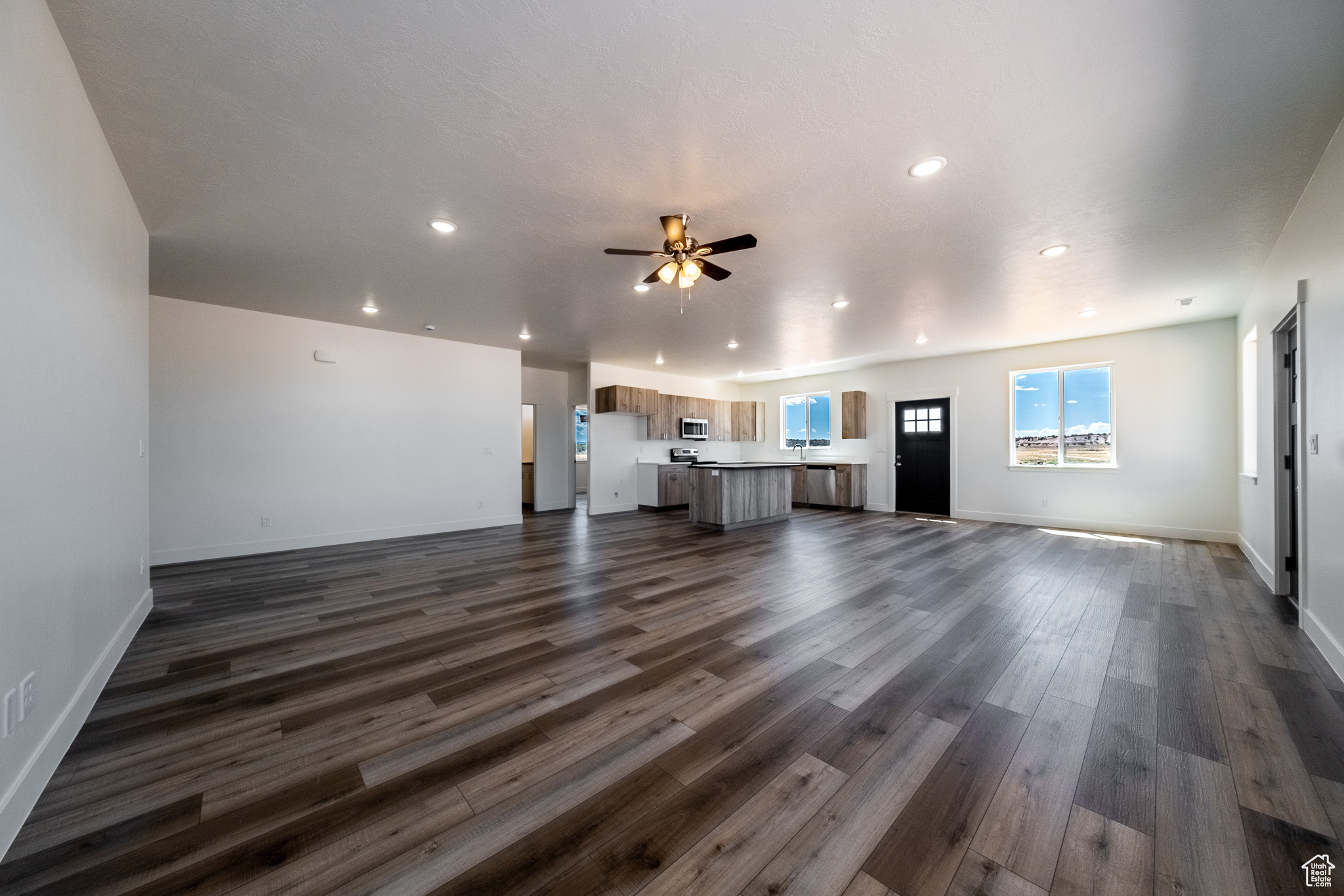 Unfurnished living room featuring recessed lighting, dark wood-type flooring, and ceiling fan