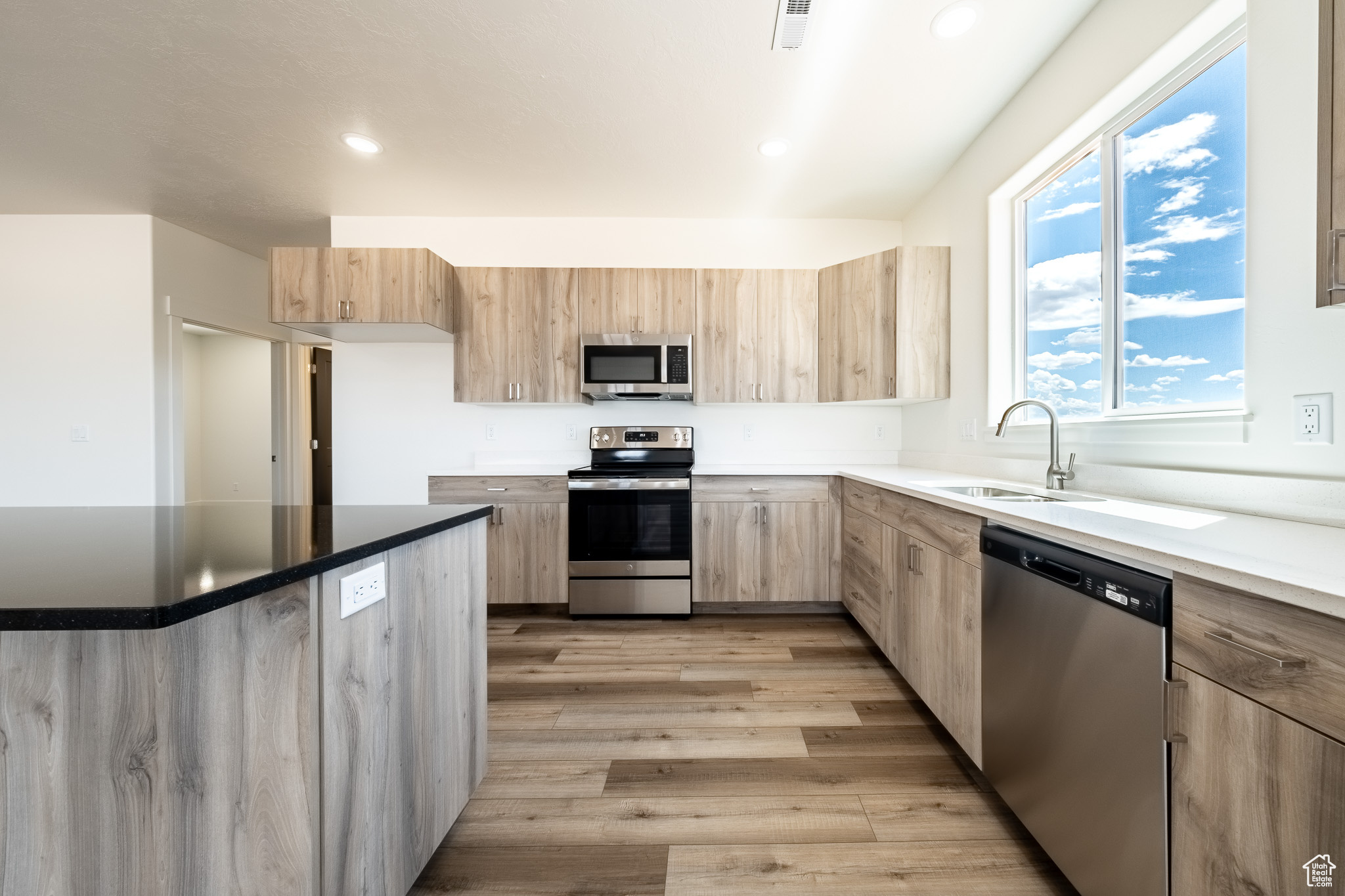 Kitchen with light brown cabinetry, visible vents, stainless steel appliances, and a sink