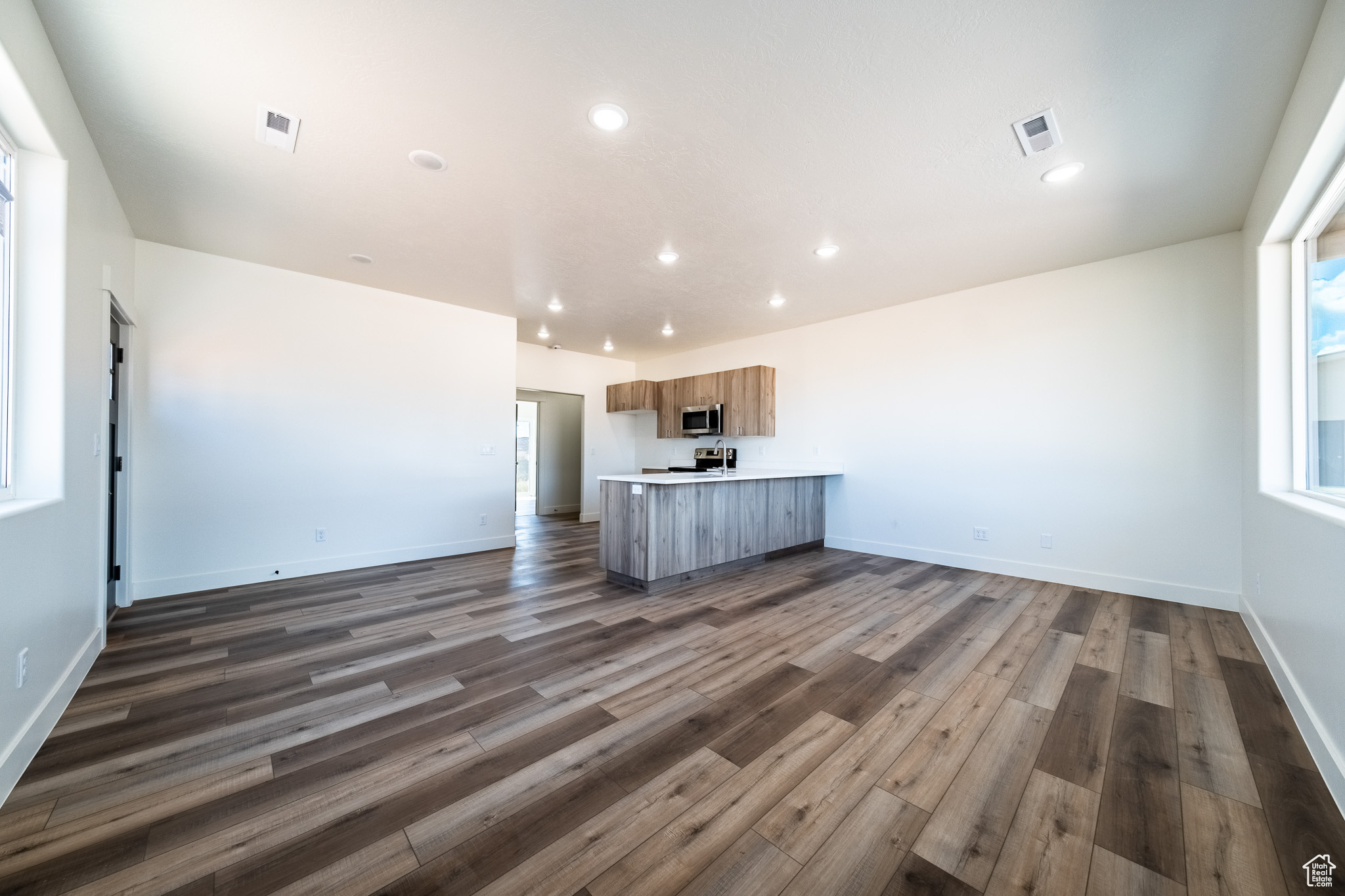 Kitchen with visible vents, open floor plan, dark wood finished floors, appliances with stainless steel finishes, and light countertops