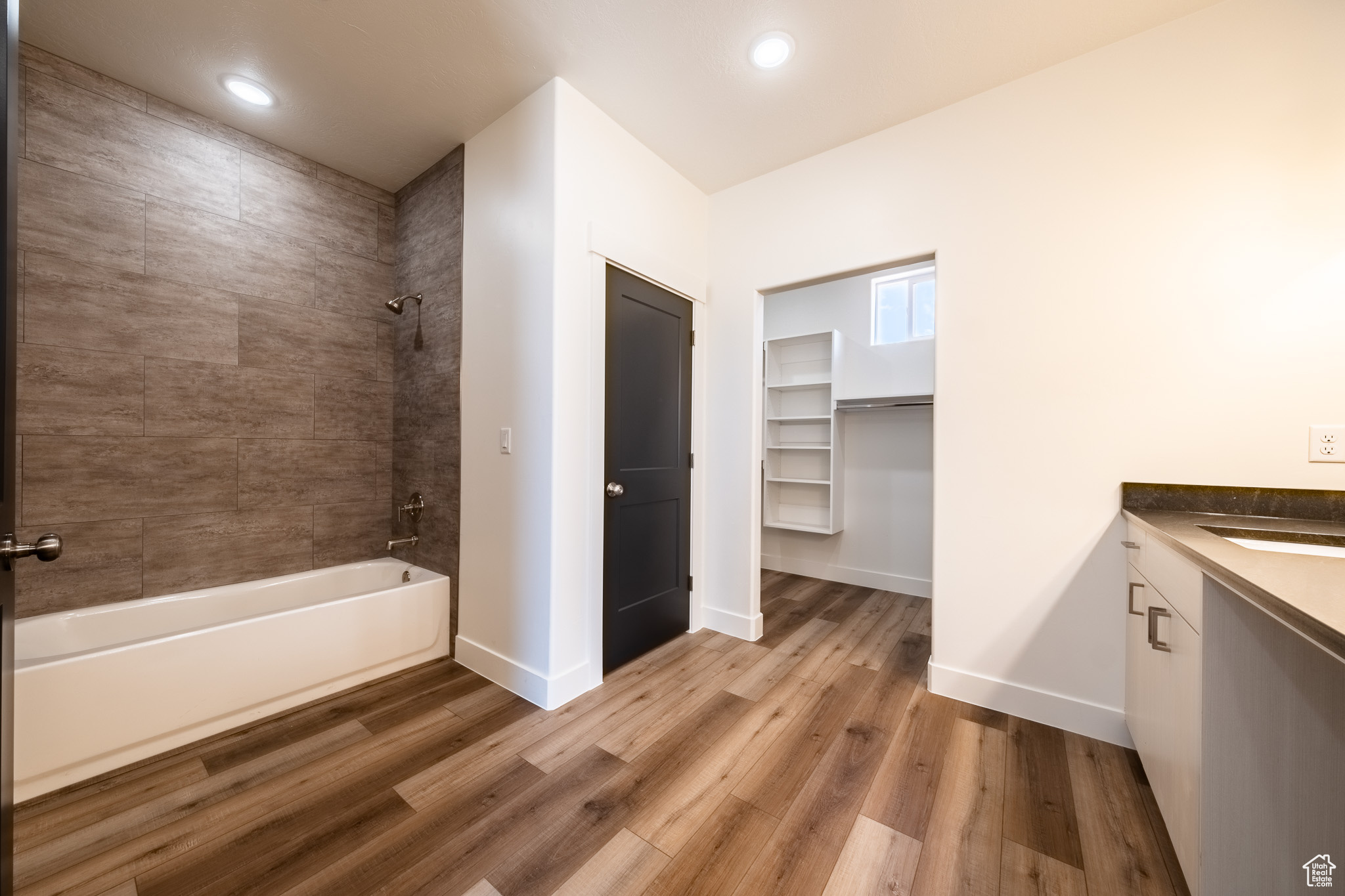 Full bath with shower / bath combination, baseboards, wood finished floors, and vanity