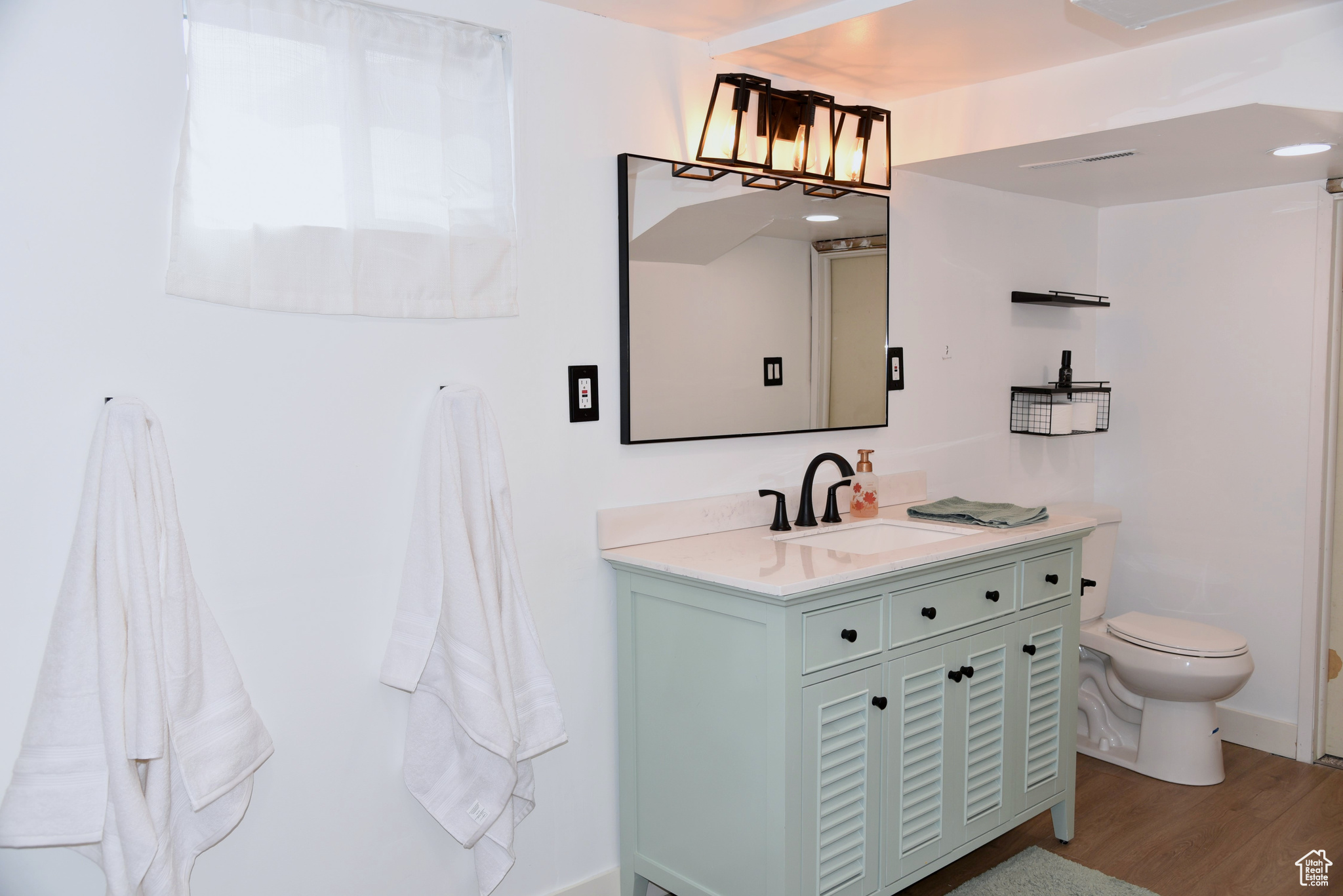 Bathroom with toilet, vanity, and wood finished floors