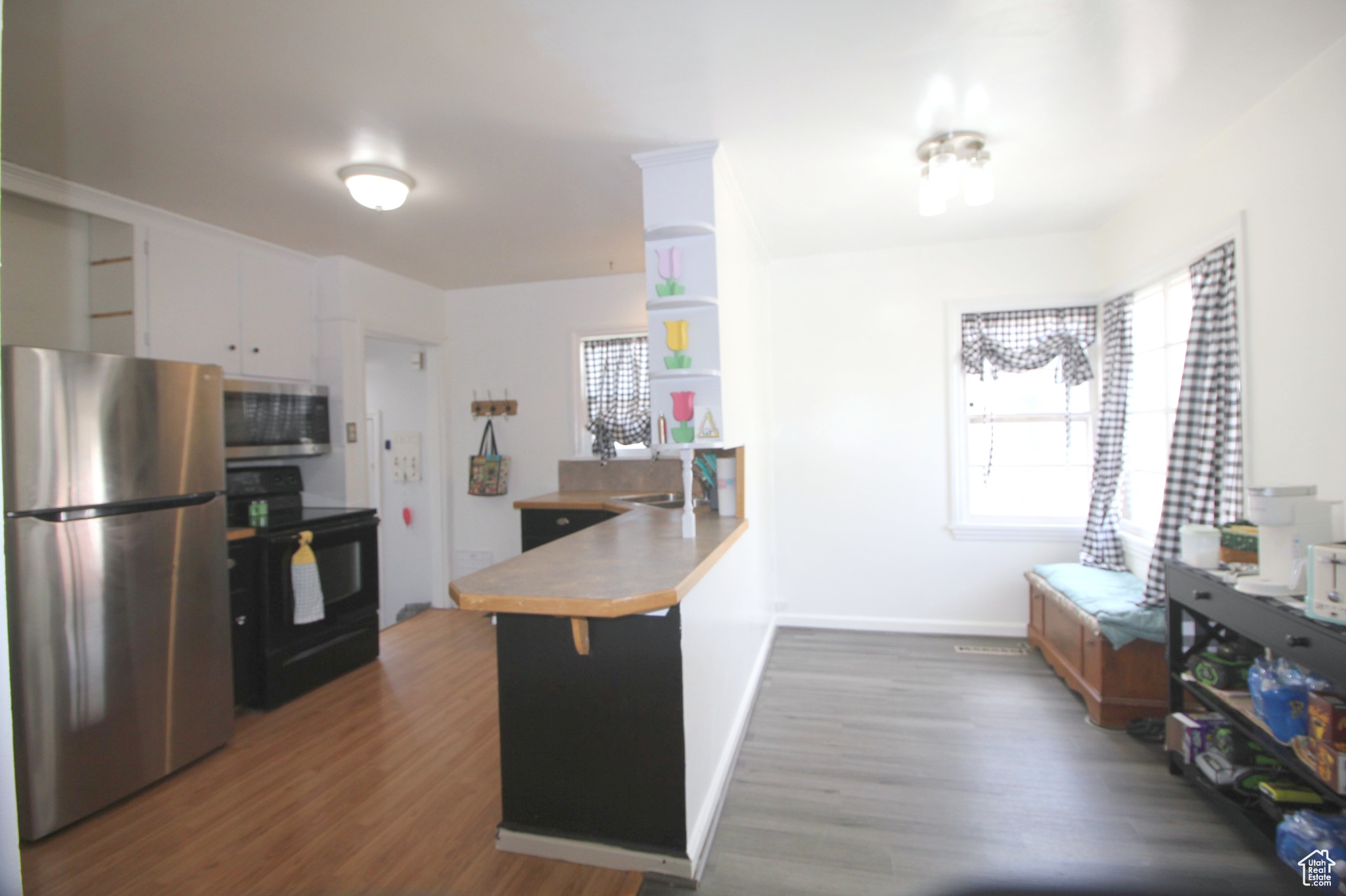 Kitchen featuring baseboards, a peninsula, dark wood-style floors, stainless steel appliances, and open shelves