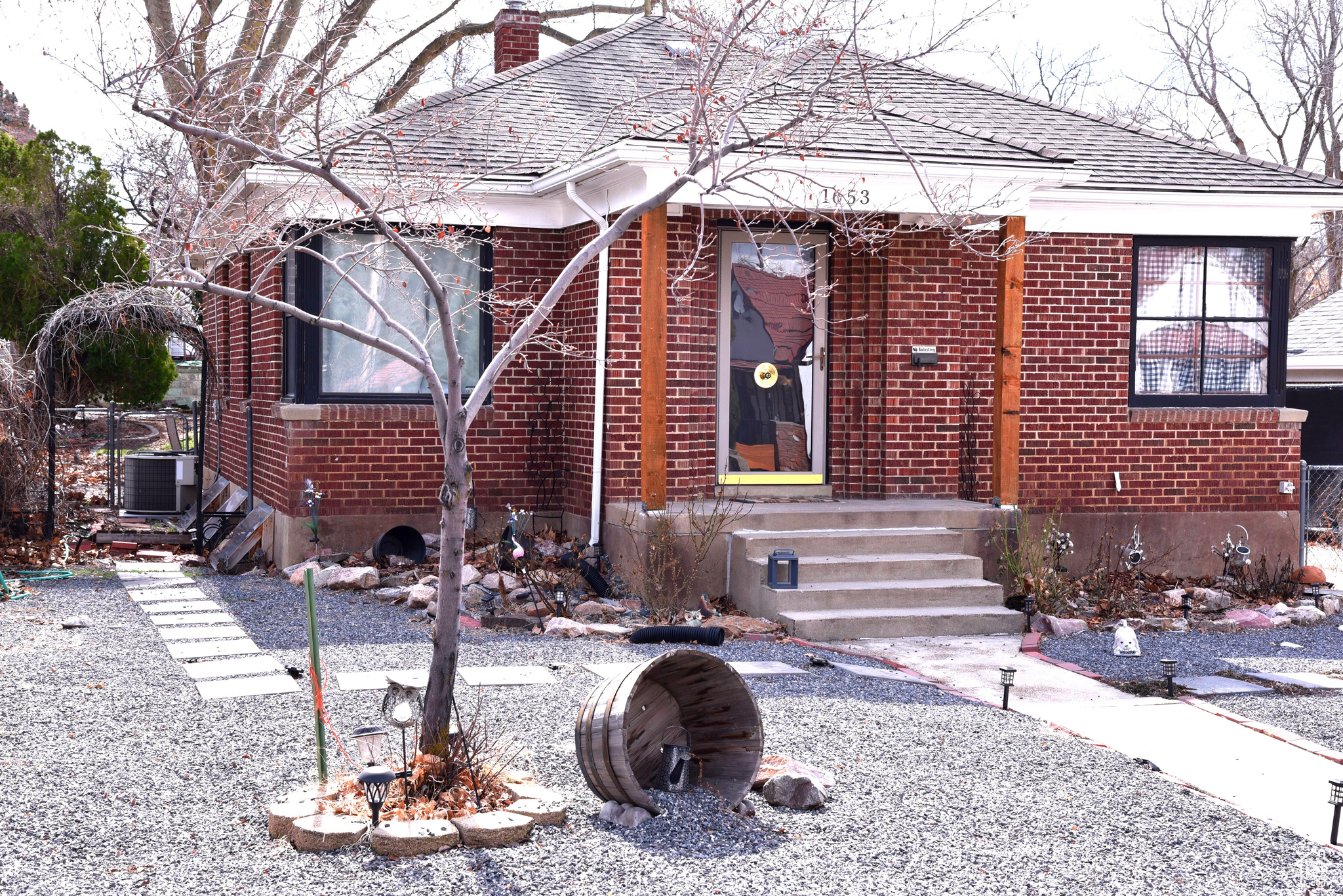 View of front of property featuring cooling unit, brick siding, roof with shingles, and a chimney