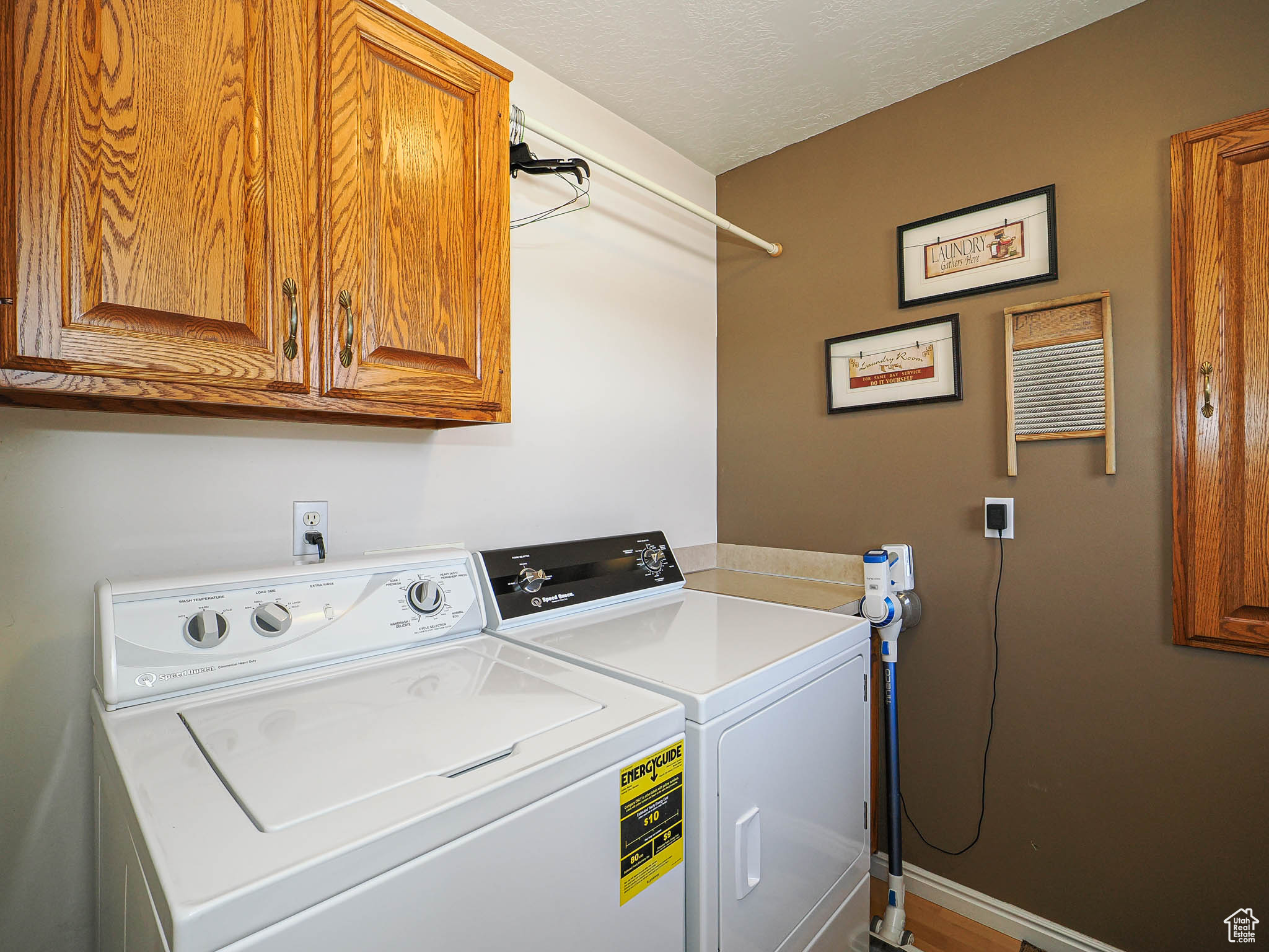 Laundry area featuring baseboards, cabinet space, a textured ceiling, and washing machine and dryer