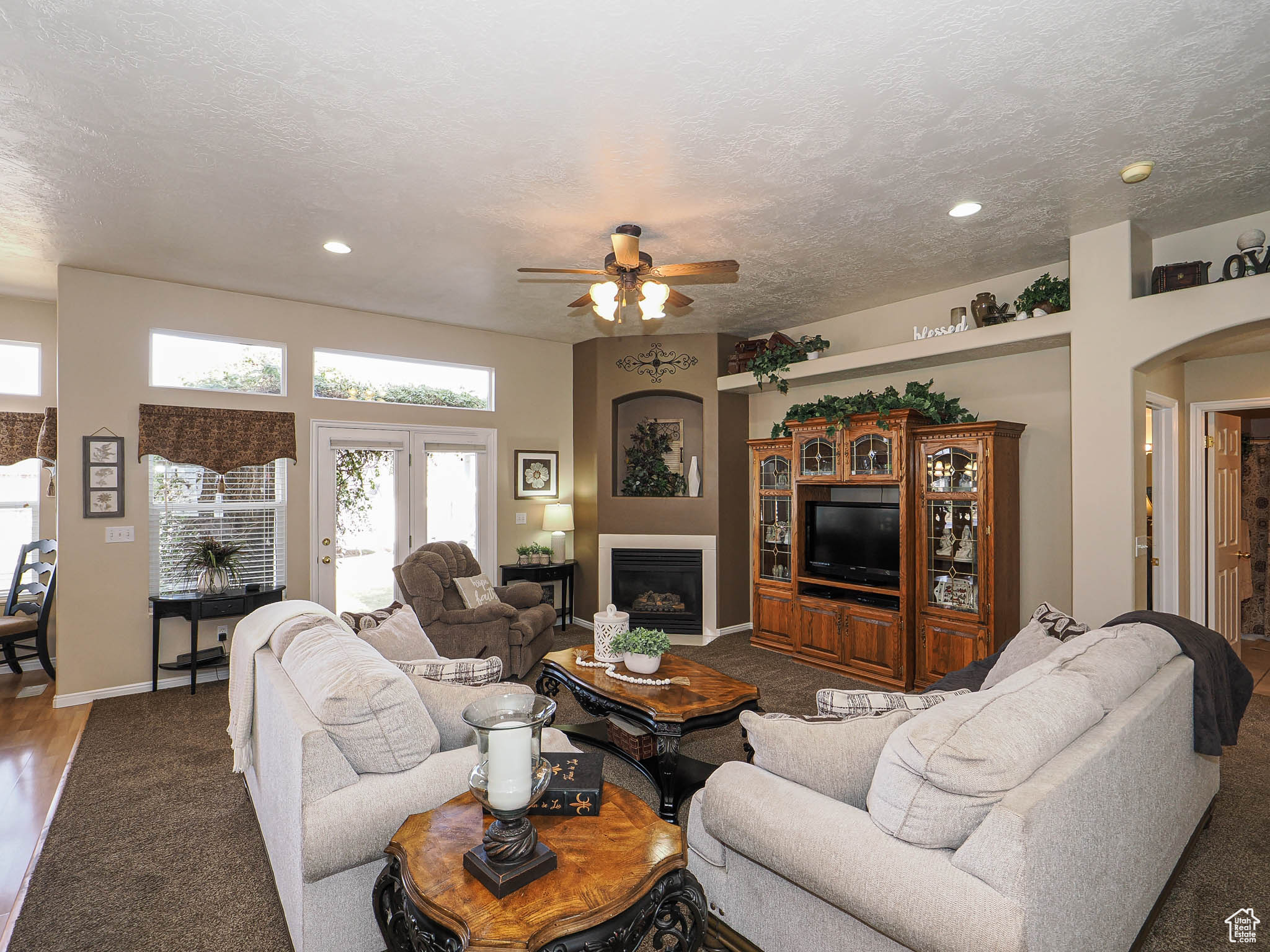 Living room with baseboards, arched walkways, a textured ceiling, and a fireplace
