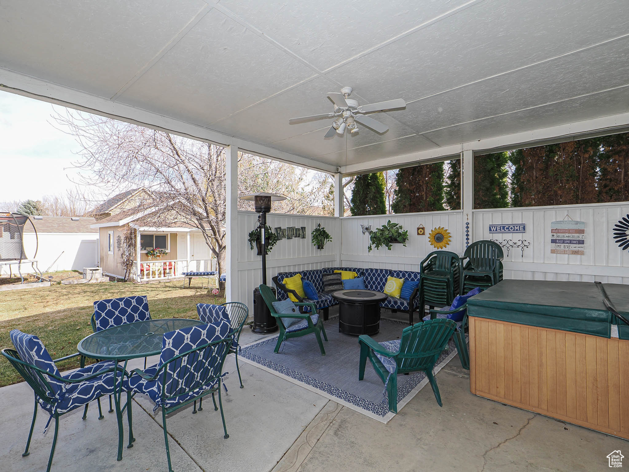 View of patio with a hot tub, a fenced backyard, an outbuilding, outdoor dining space, and a ceiling fan