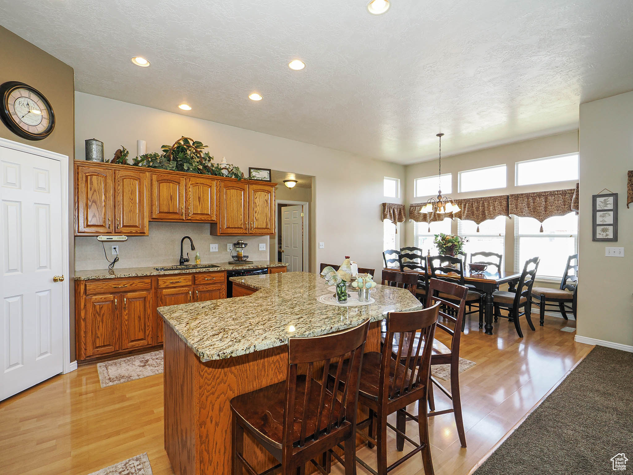 Kitchen with light stone counters, a kitchen island, a sink, a kitchen bar, and brown cabinets