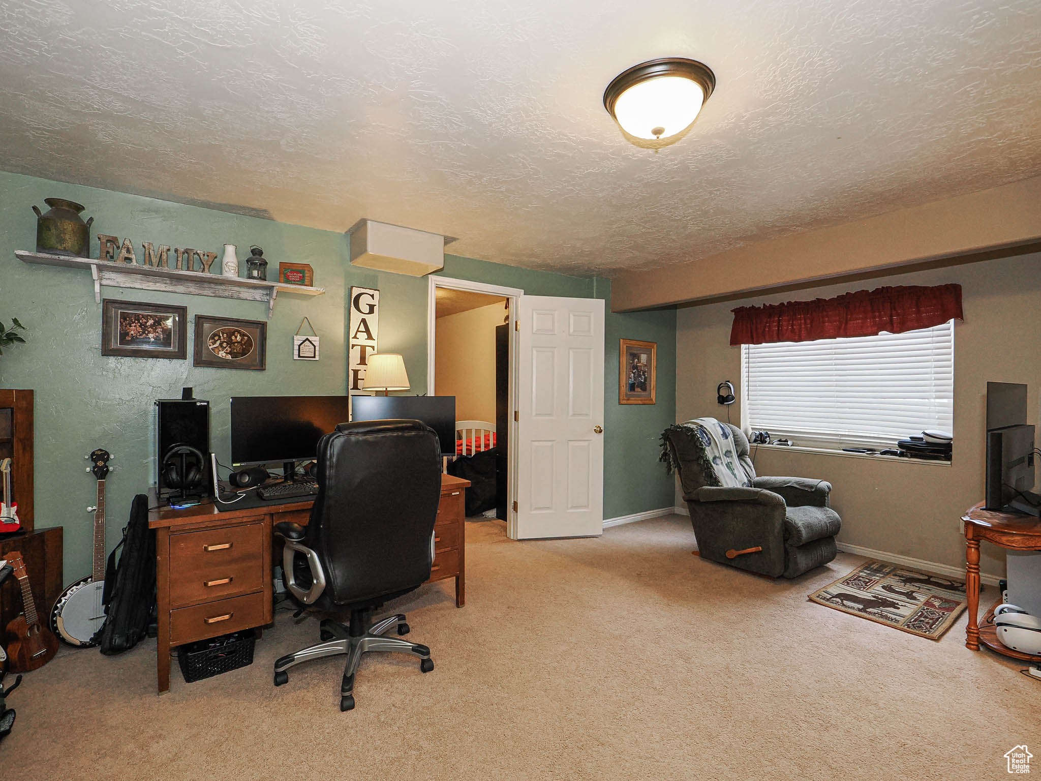 Home office with carpet flooring, baseboards, and a textured ceiling