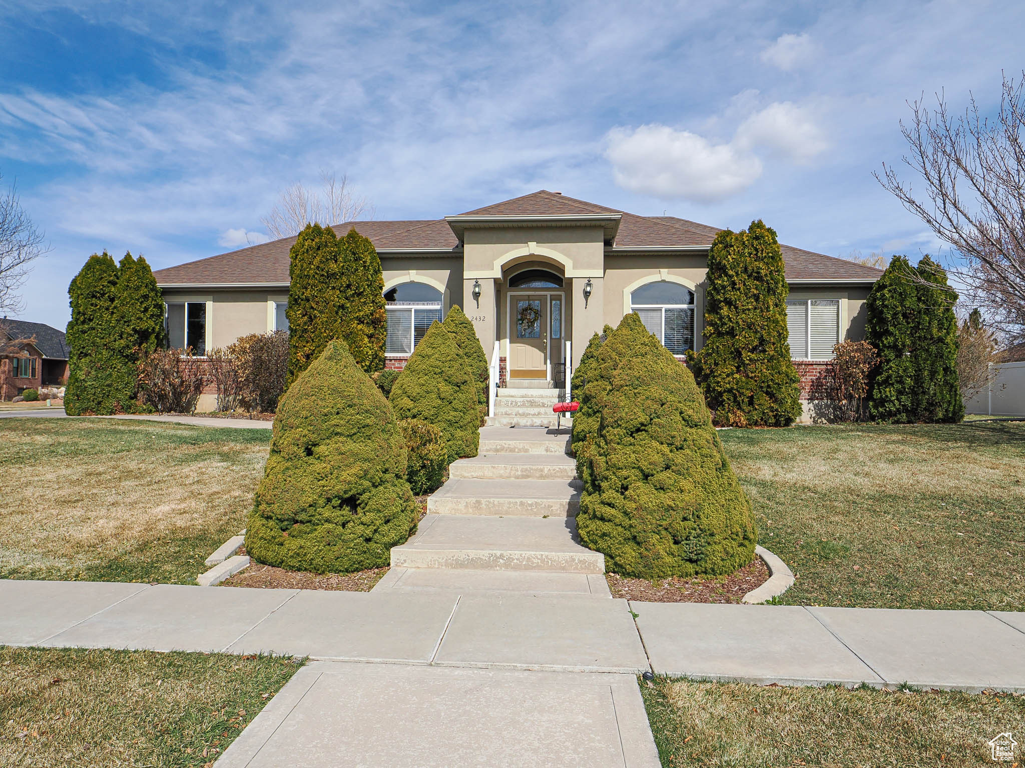 View of front of house with stucco siding, a front yard, and a shingled roof