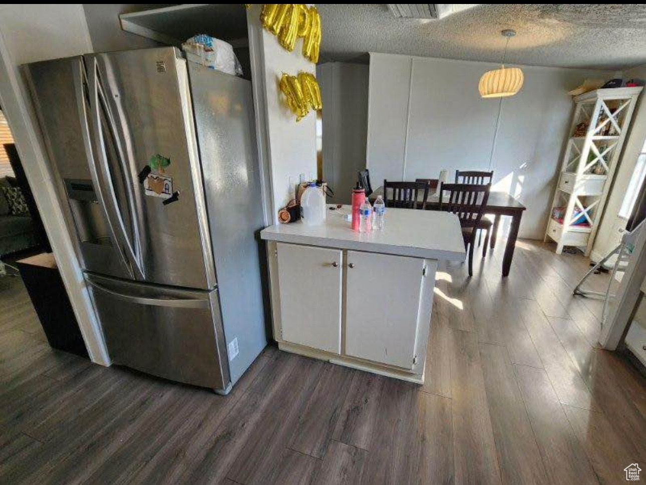 Kitchen featuring dark wood-style floors, light countertops, a textured ceiling, white cabinetry, and stainless steel fridge
