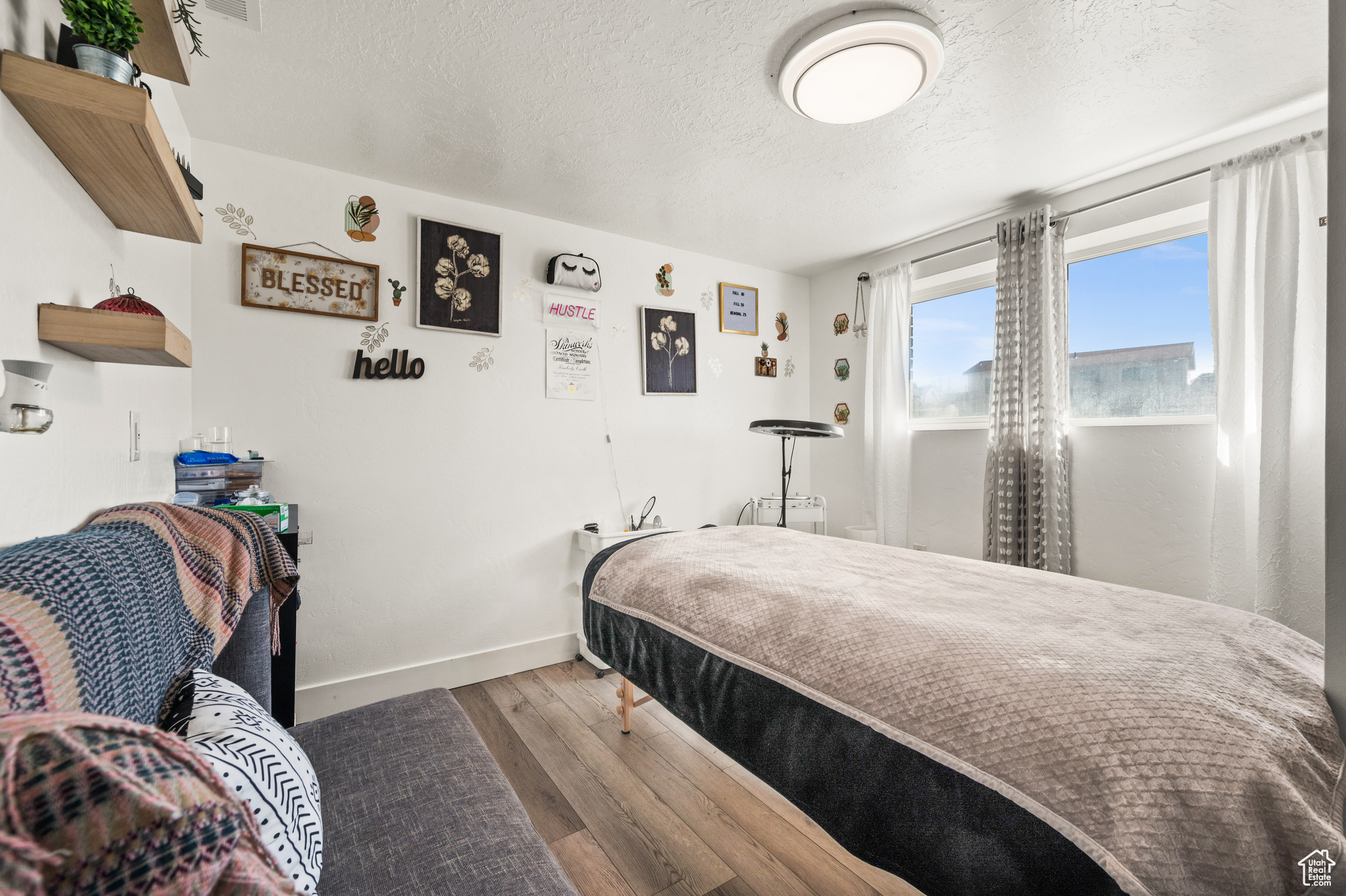 Bedroom with wood finished floors, baseboards, and a textured ceiling