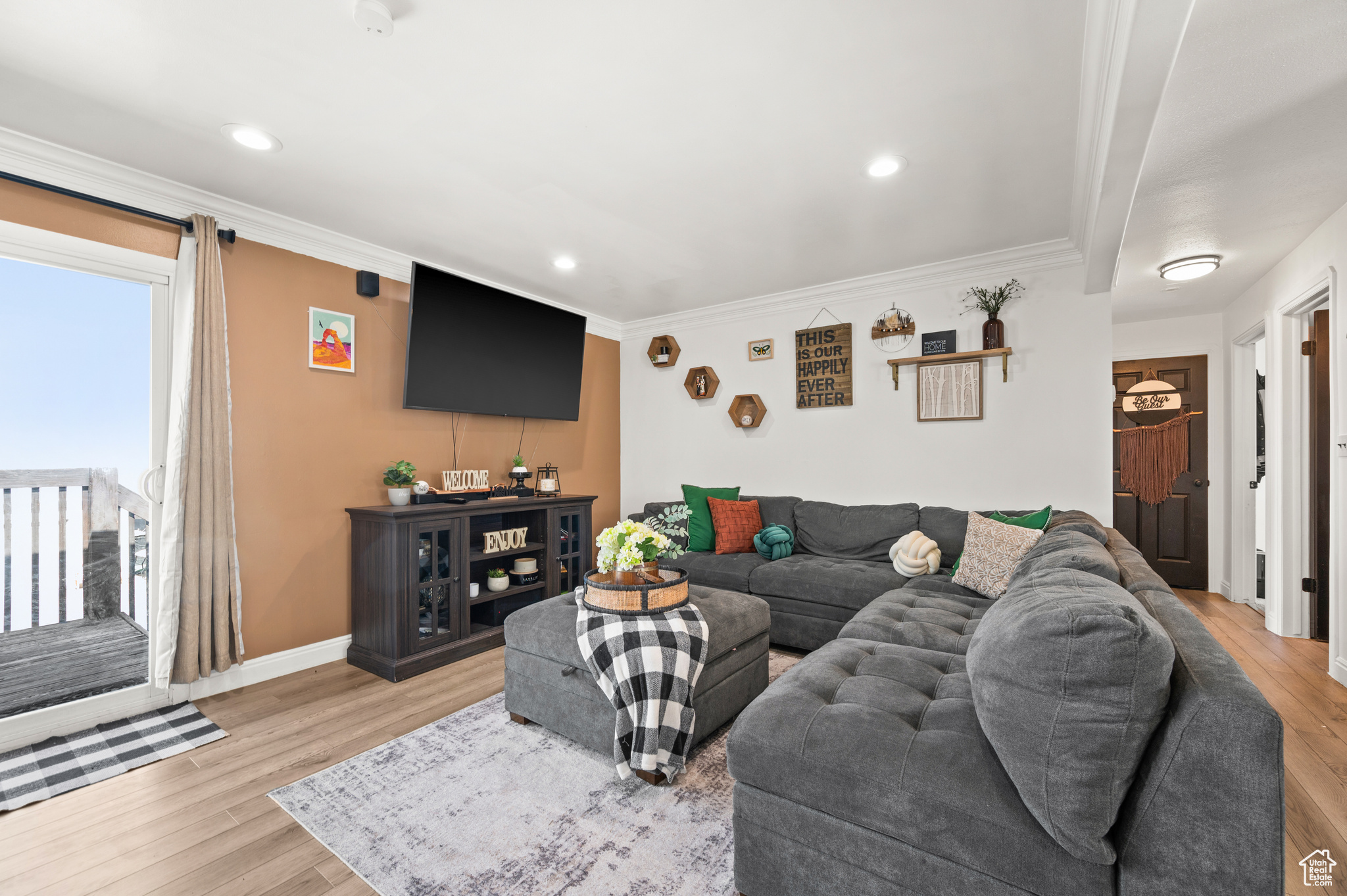 Living room featuring light wood-type flooring, baseboards, and ornamental molding