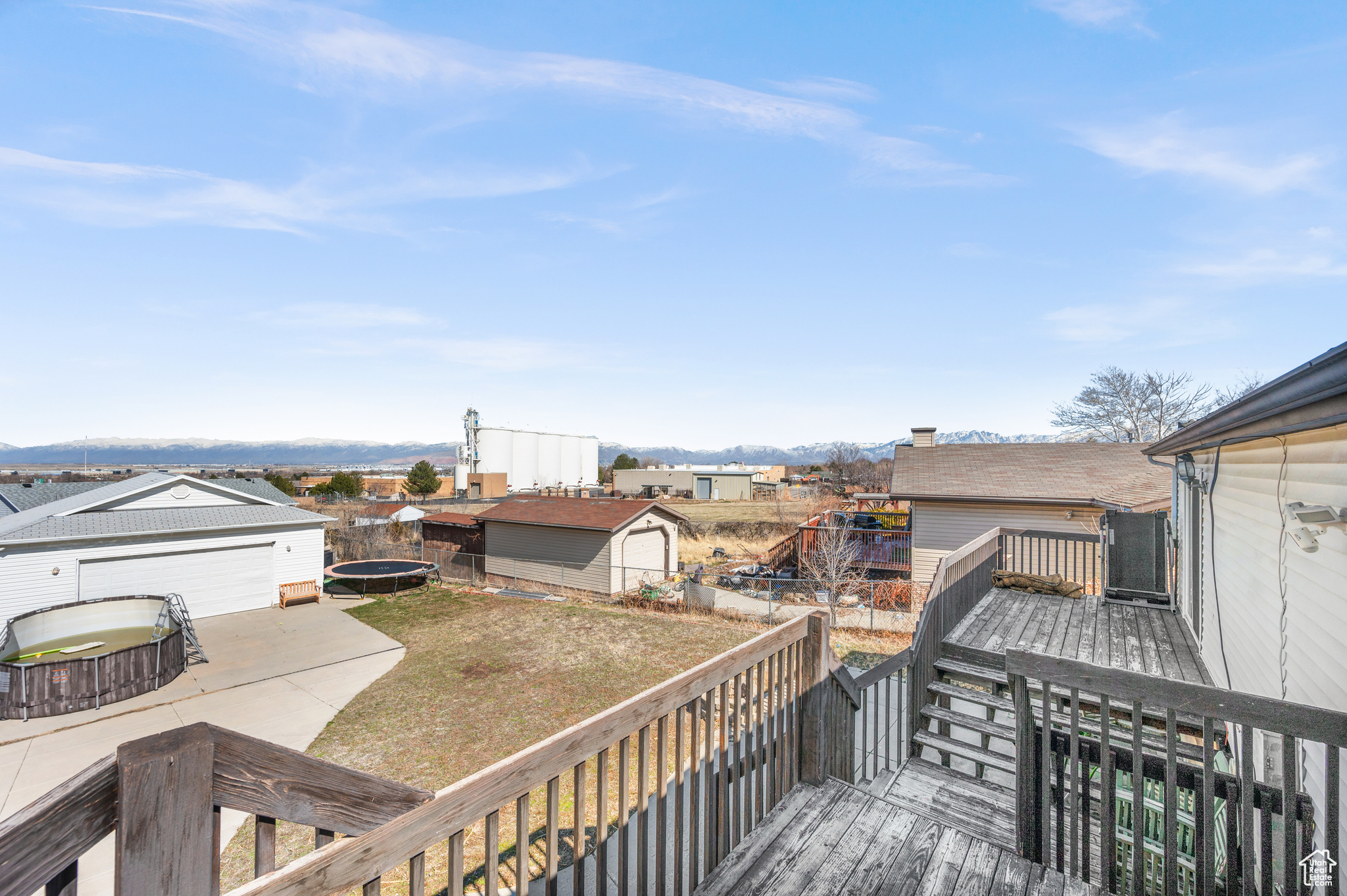 Wooden terrace with an outbuilding, a trampoline, and a lawn