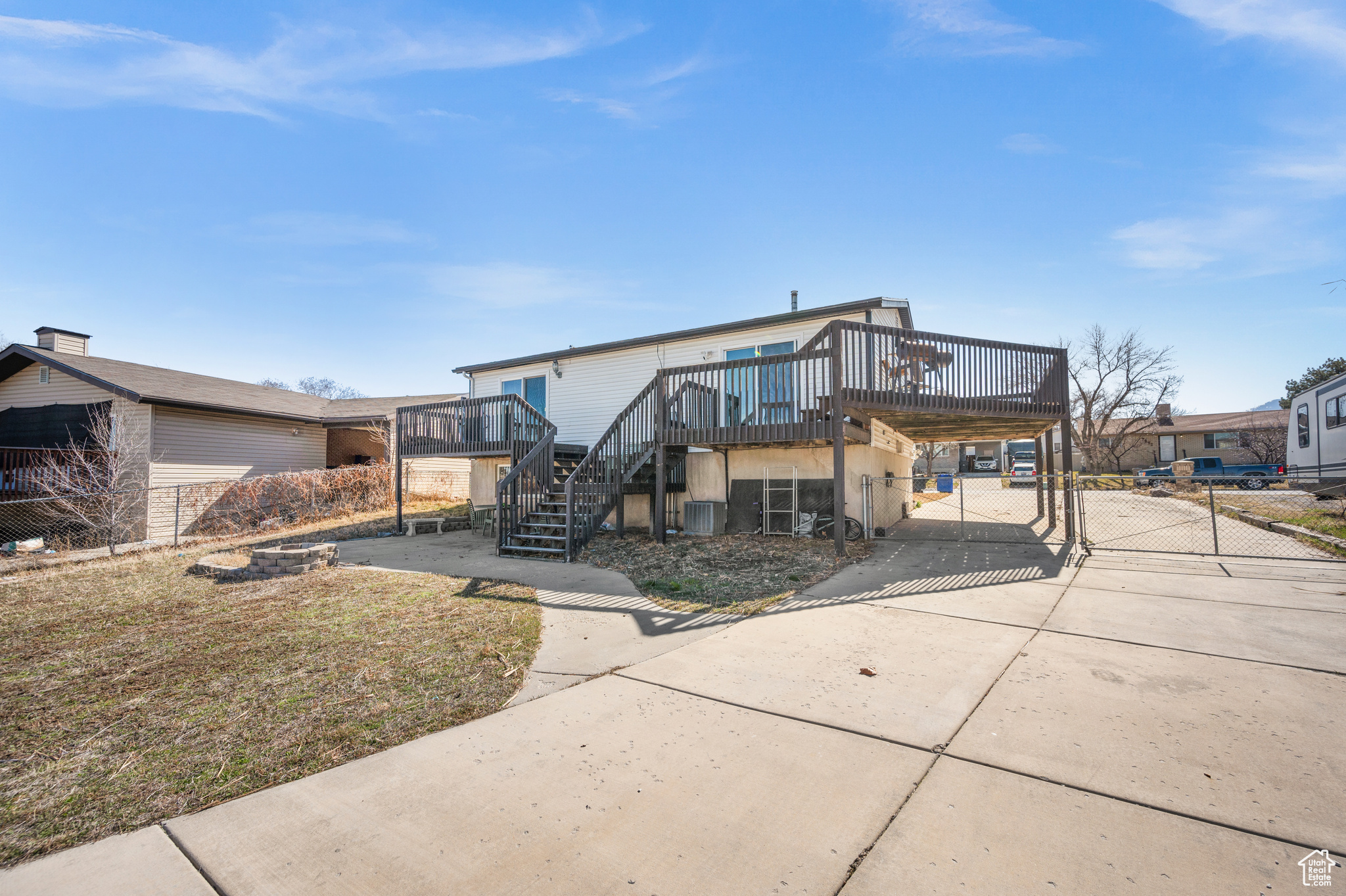 View of front of property with a deck, a gate, fence, concrete driveway, and stairs