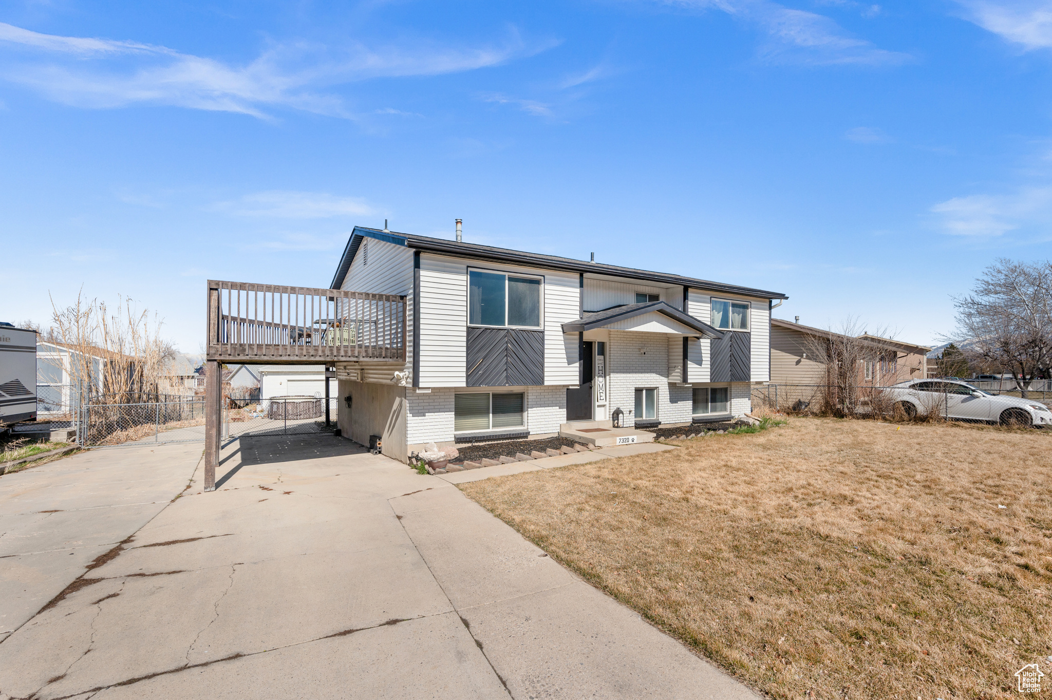 Bi-level home with concrete driveway, fence, brick siding, and a front yard