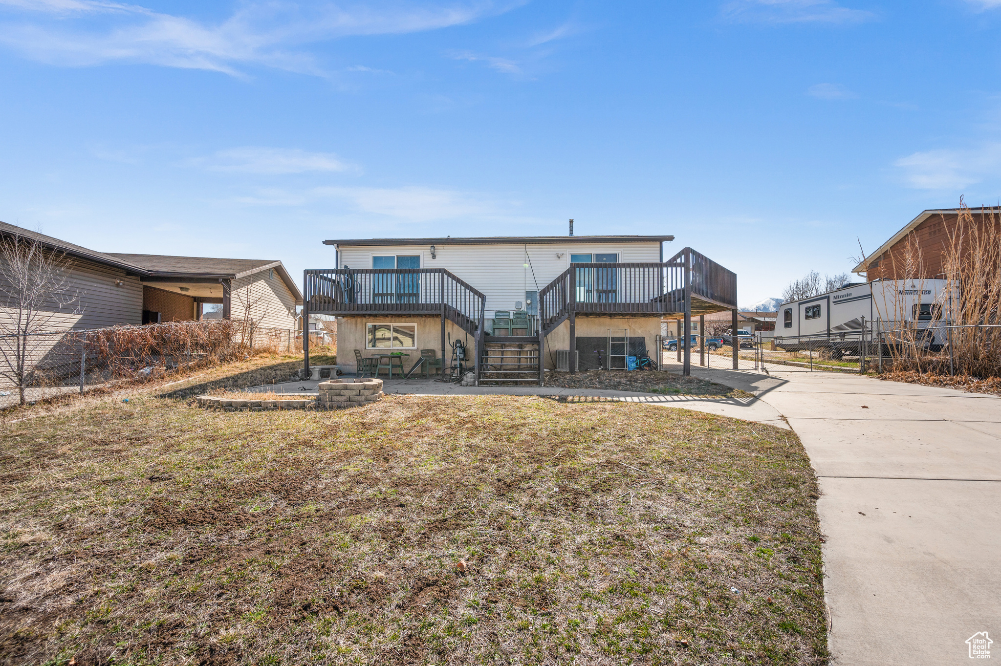 View of front of home with a fire pit, fence, a wooden deck, stairs, and a front yard