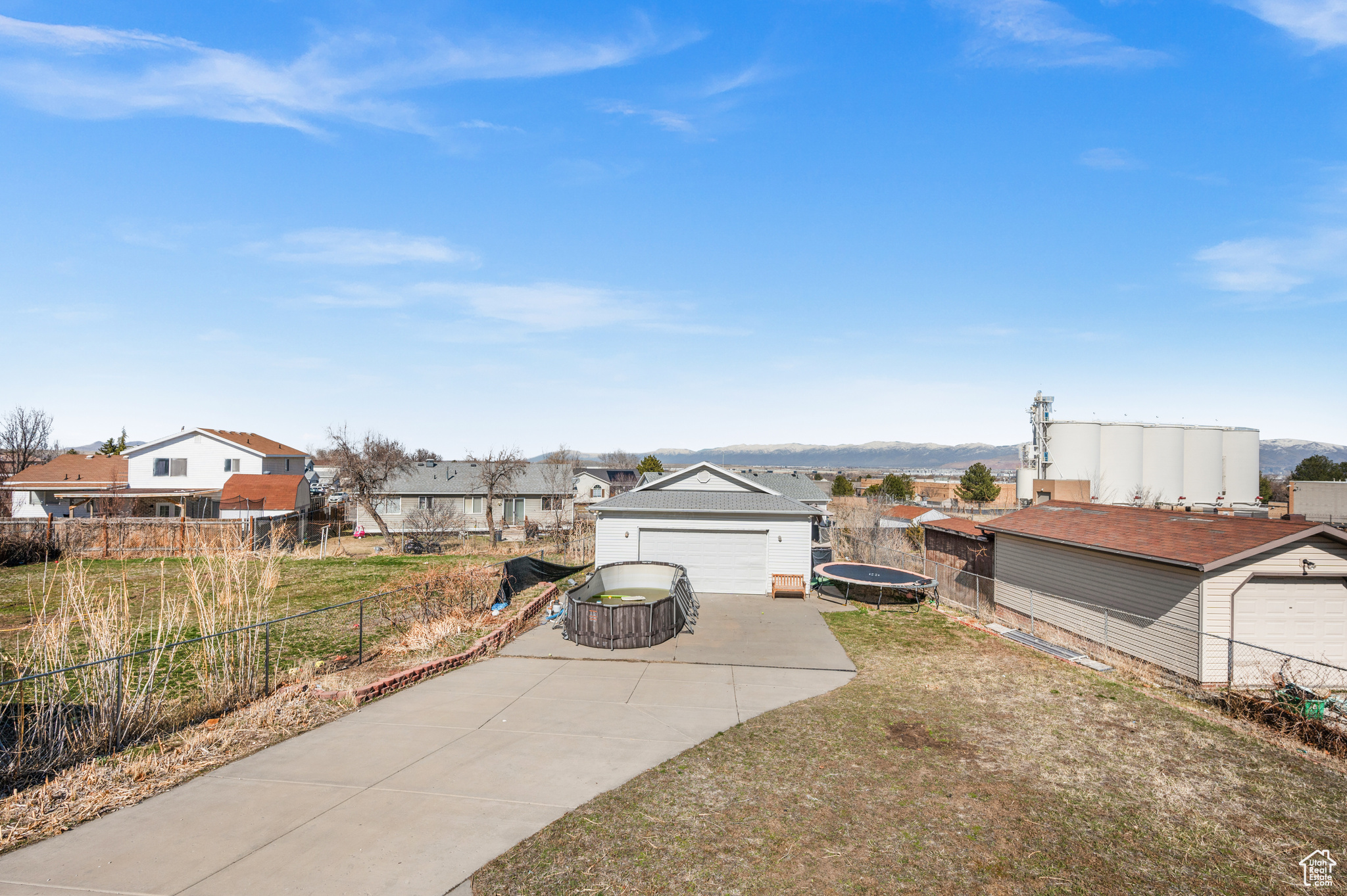 View of yard featuring an outbuilding, a residential view, a trampoline, and fence