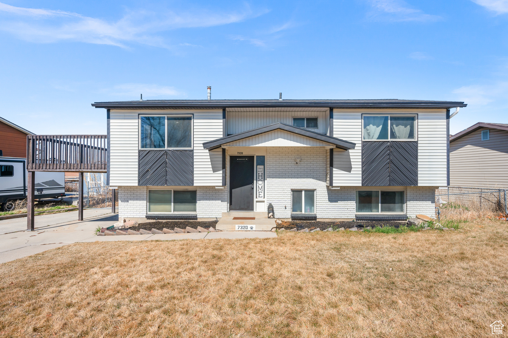 Split foyer home featuring brick siding, a front yard, and fence