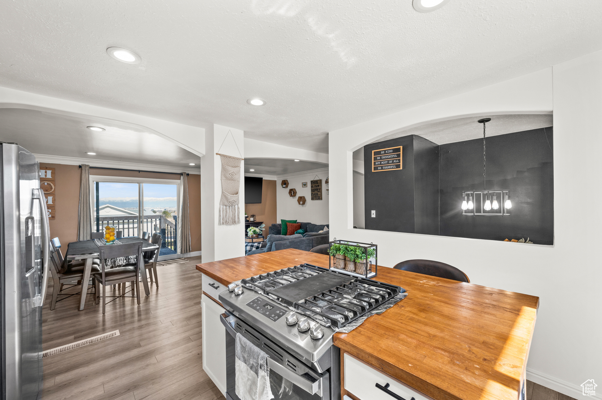 Kitchen with butcher block countertops, white cabinets, stainless steel appliances, and light wood-style floors