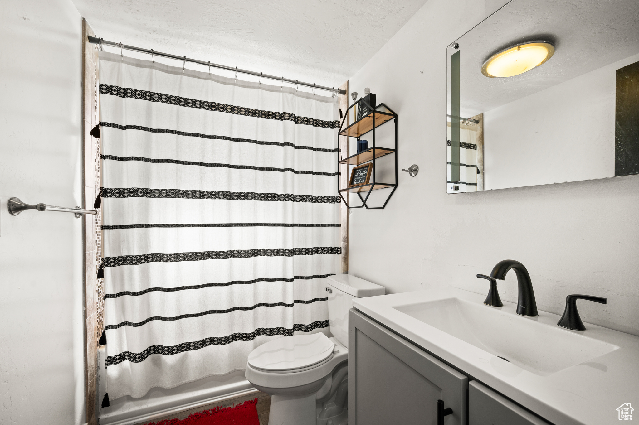 Bathroom featuring vanity, toilet, shower / bathtub combination with curtain, and a textured ceiling