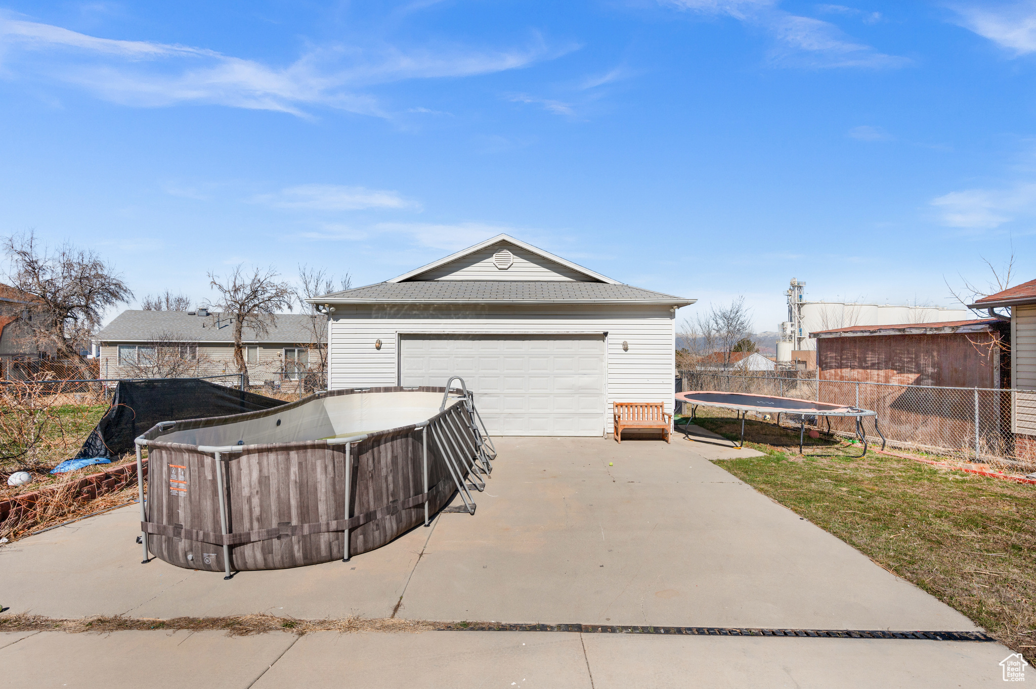 Exterior space featuring concrete driveway, a trampoline, and fence