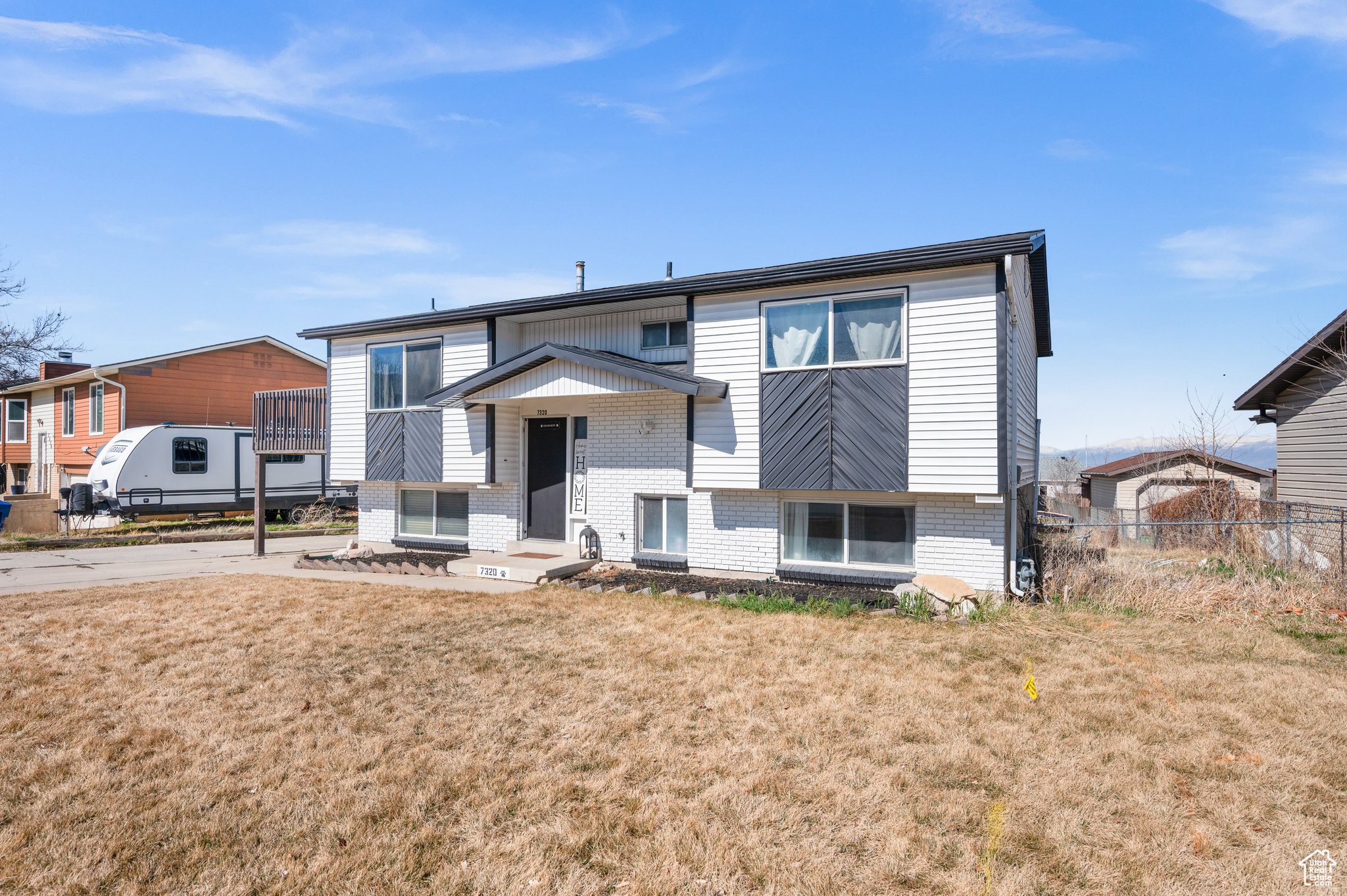 View of front of property with entry steps, brick siding, a front yard, and fence