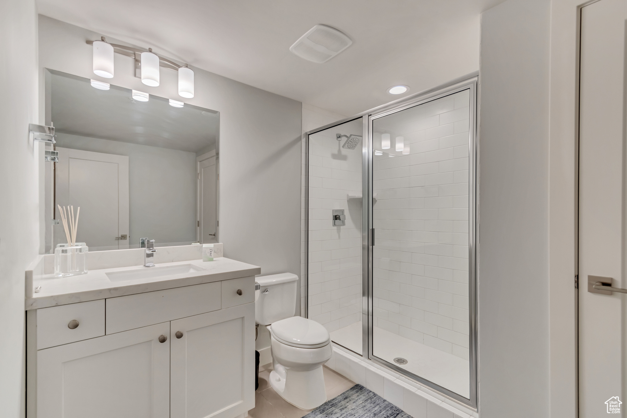 Bathroom featuring vanity, toilet, and a stall shower