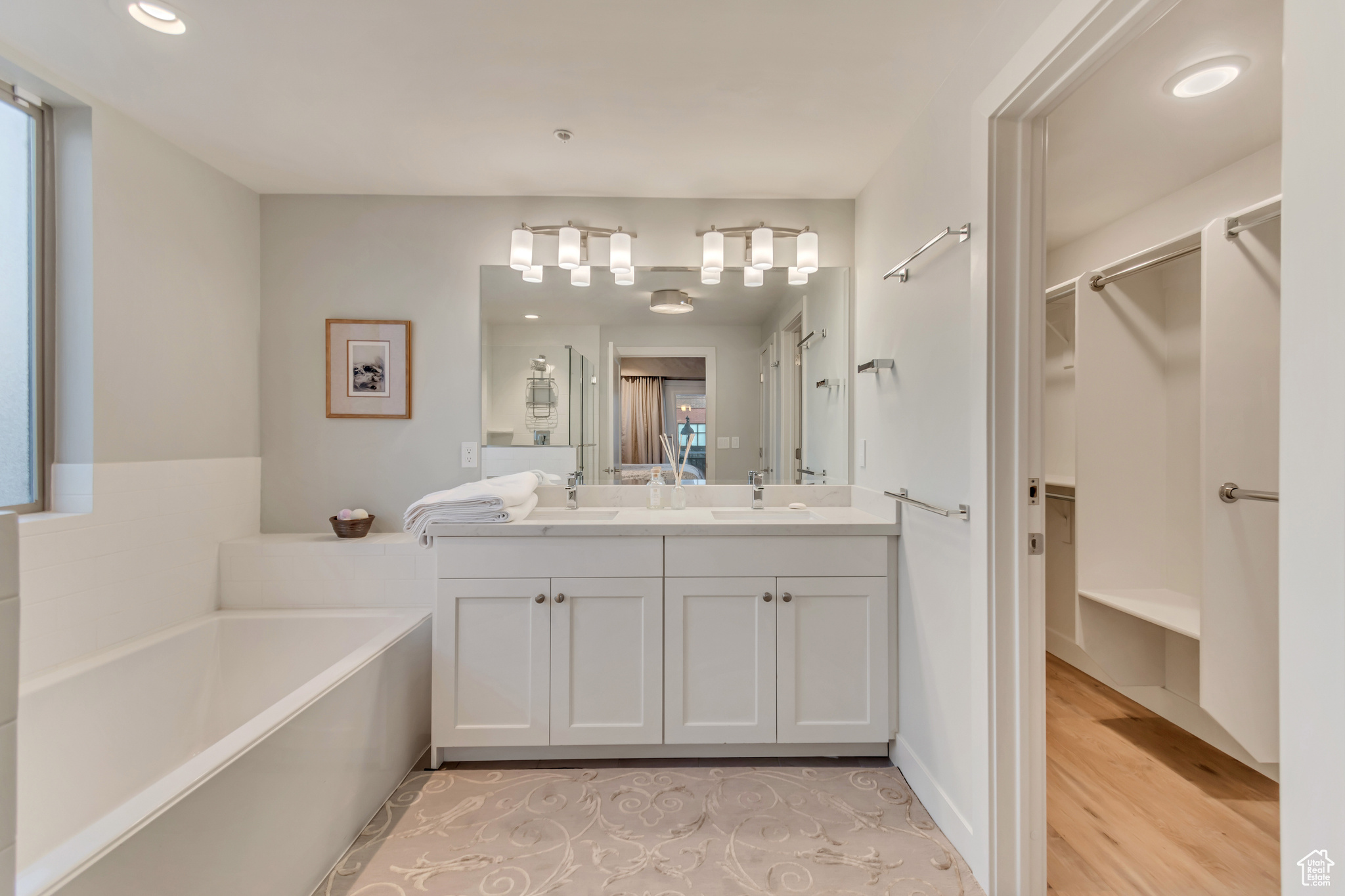 Bathroom featuring double vanity, a walk in closet, a bath, and a sink