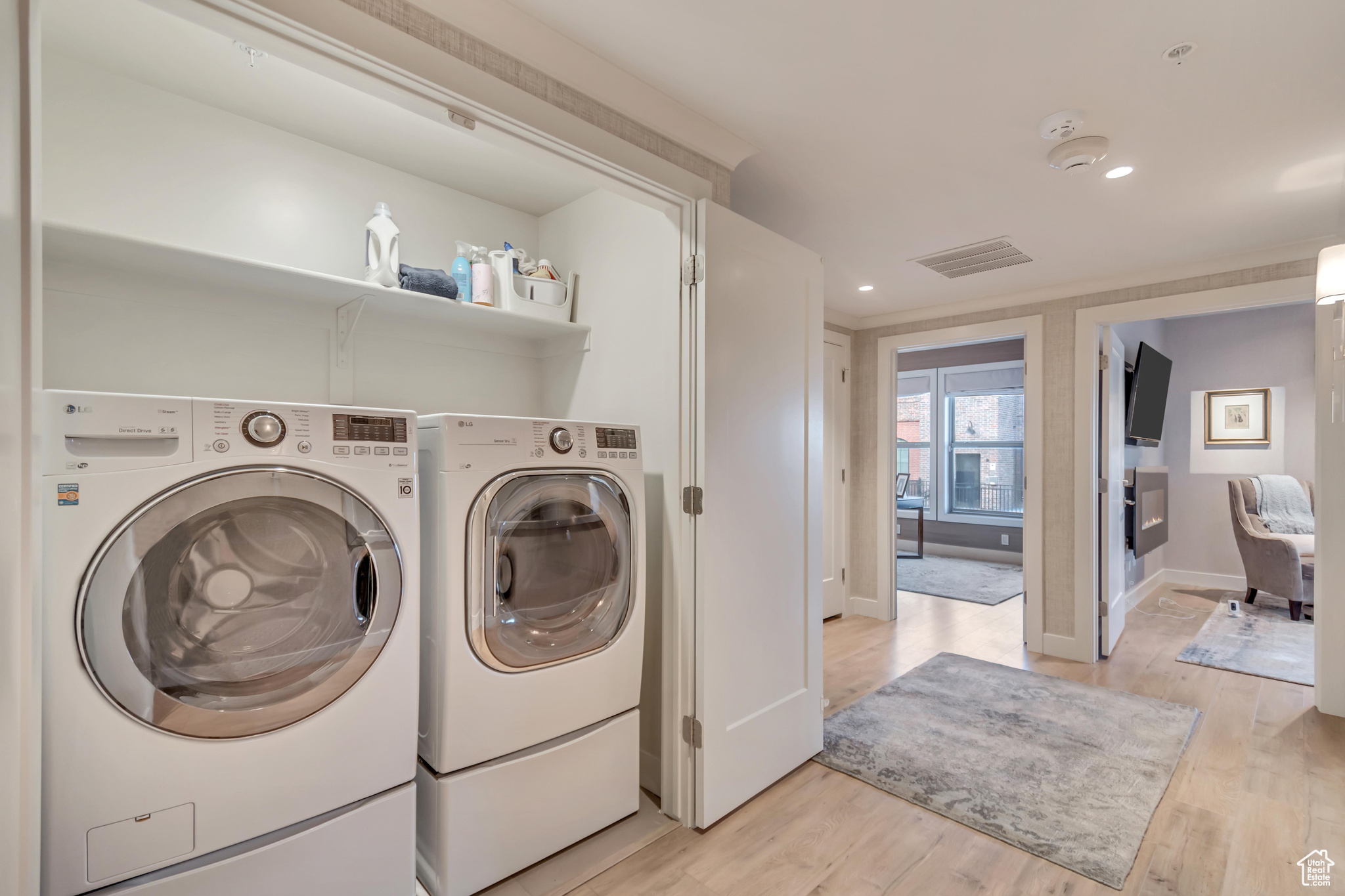 Washroom with washing machine and clothes dryer, visible vents, baseboards, laundry area, and light wood-style floors